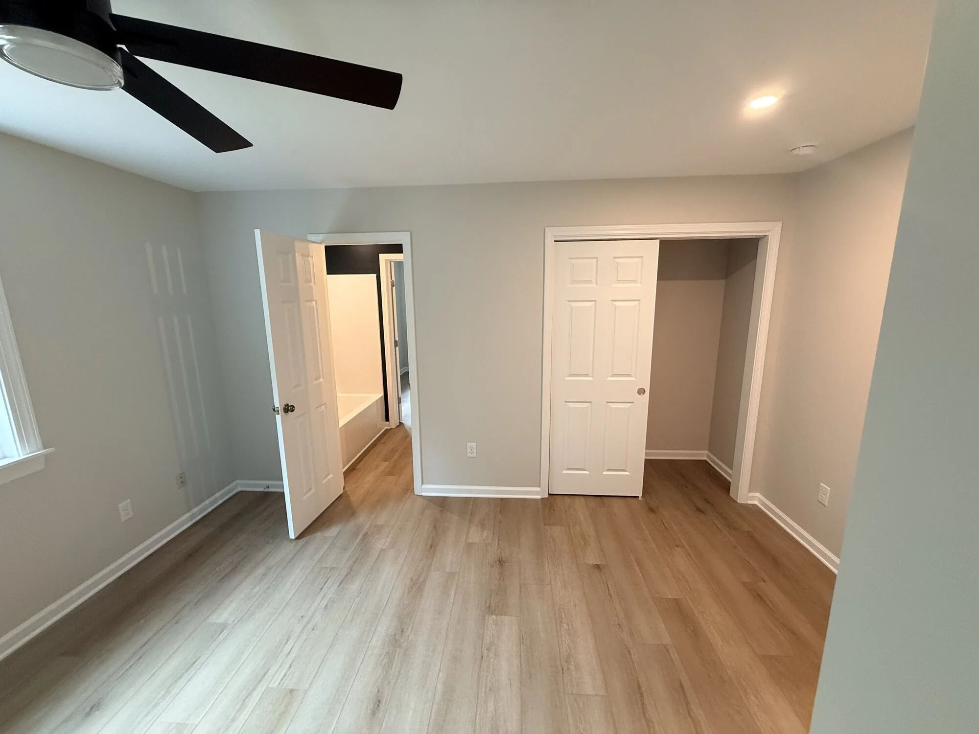 After — upstairs bedroom finished with new flooring, paint, and modern fan