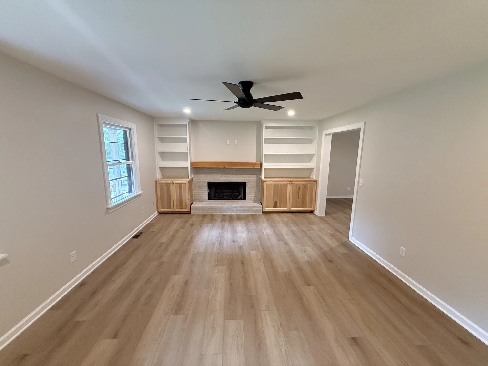 After — living room transformed with custom built-ins, refinished fireplace, and new floors