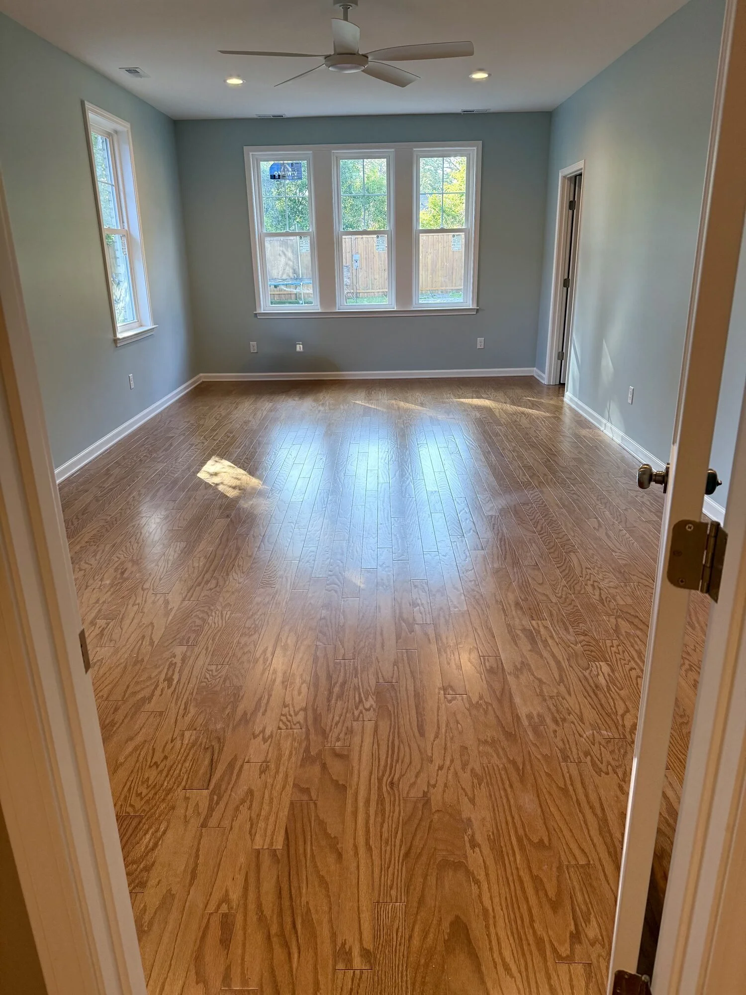 After — the master bedroom with triple window and hardwood floors