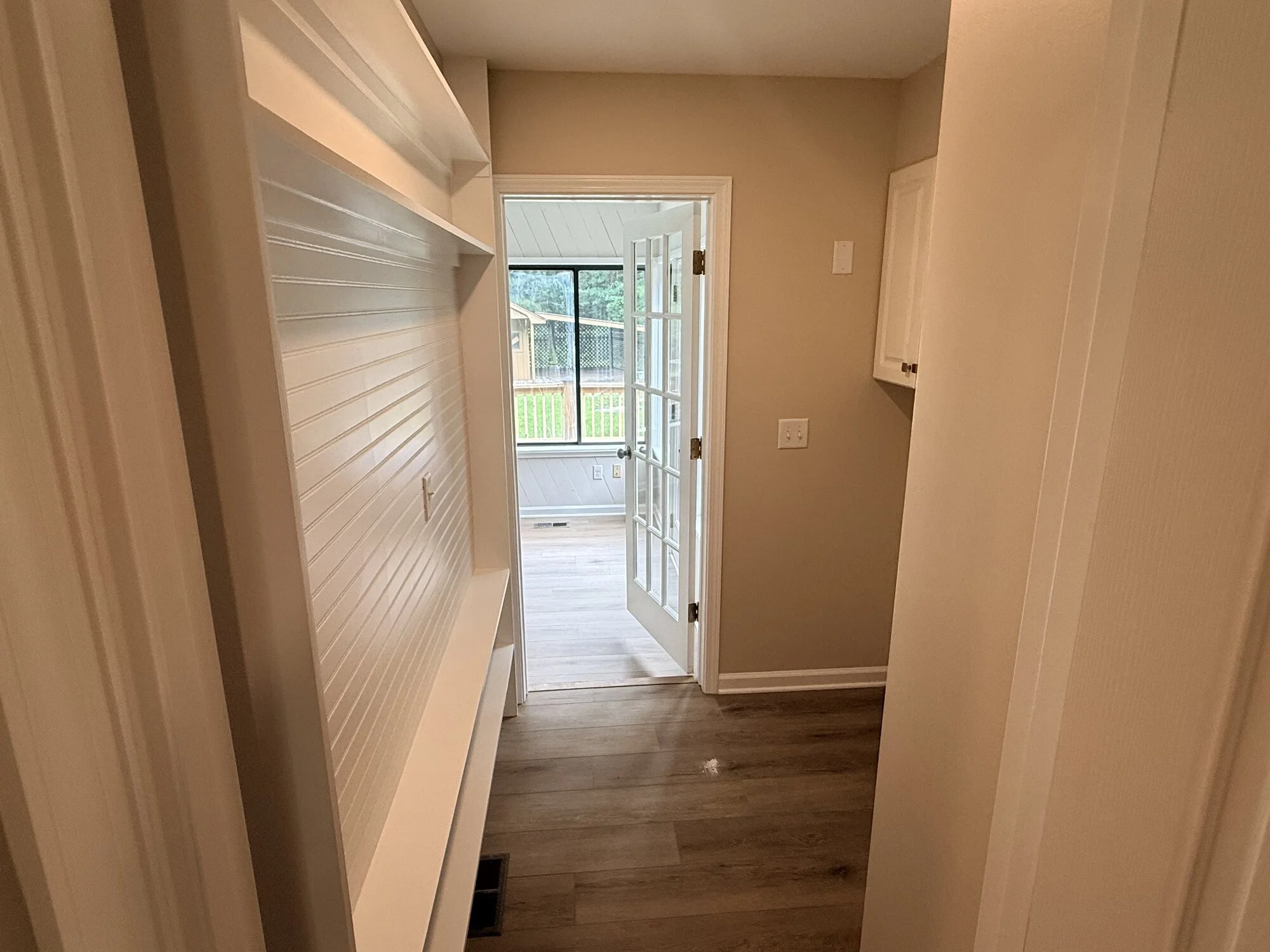 After — the same passage opened up with new flooring, paint, and glass door to the sunroom