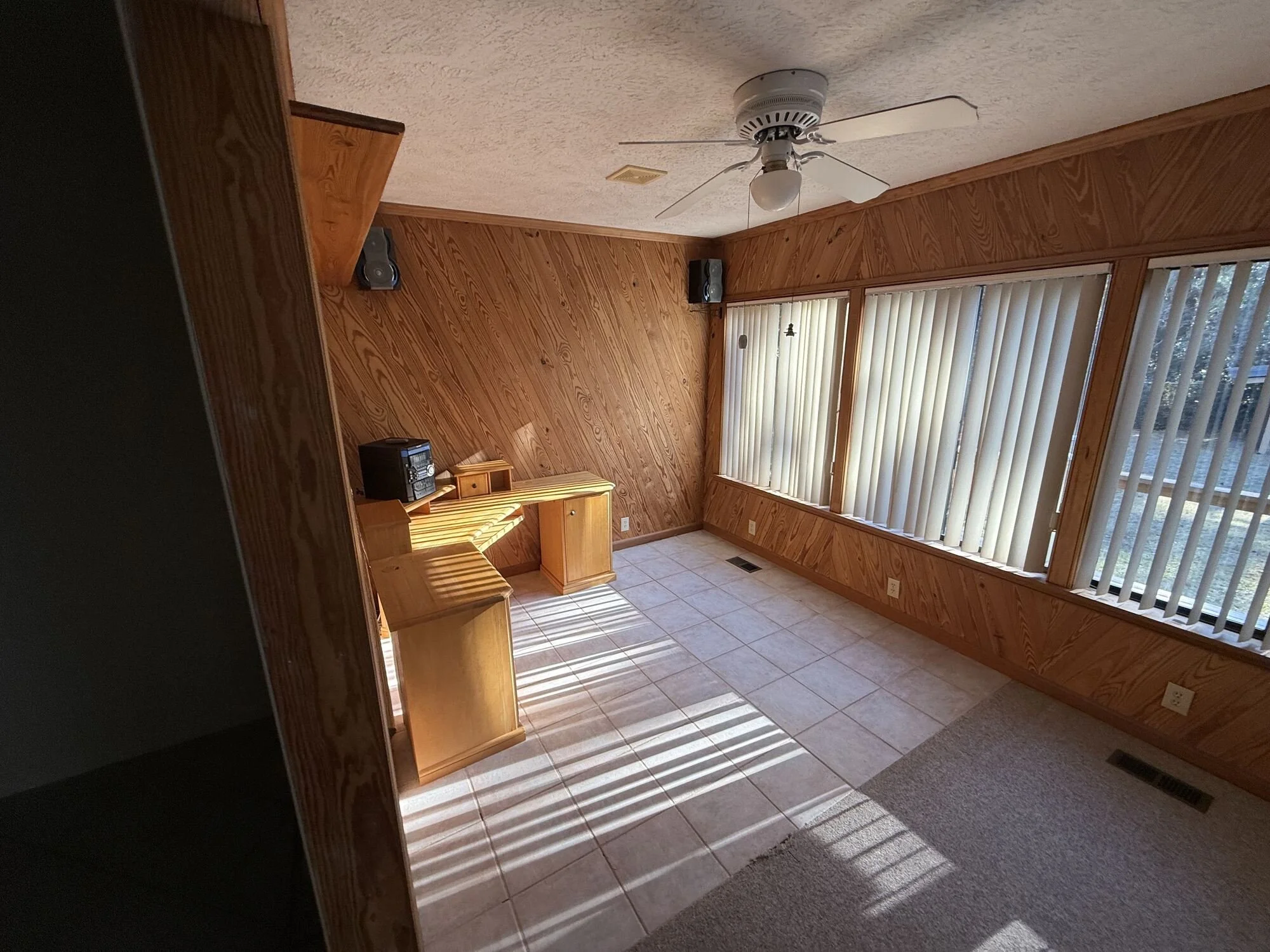 Before — sunroom with dark wood paneling and worn finishes