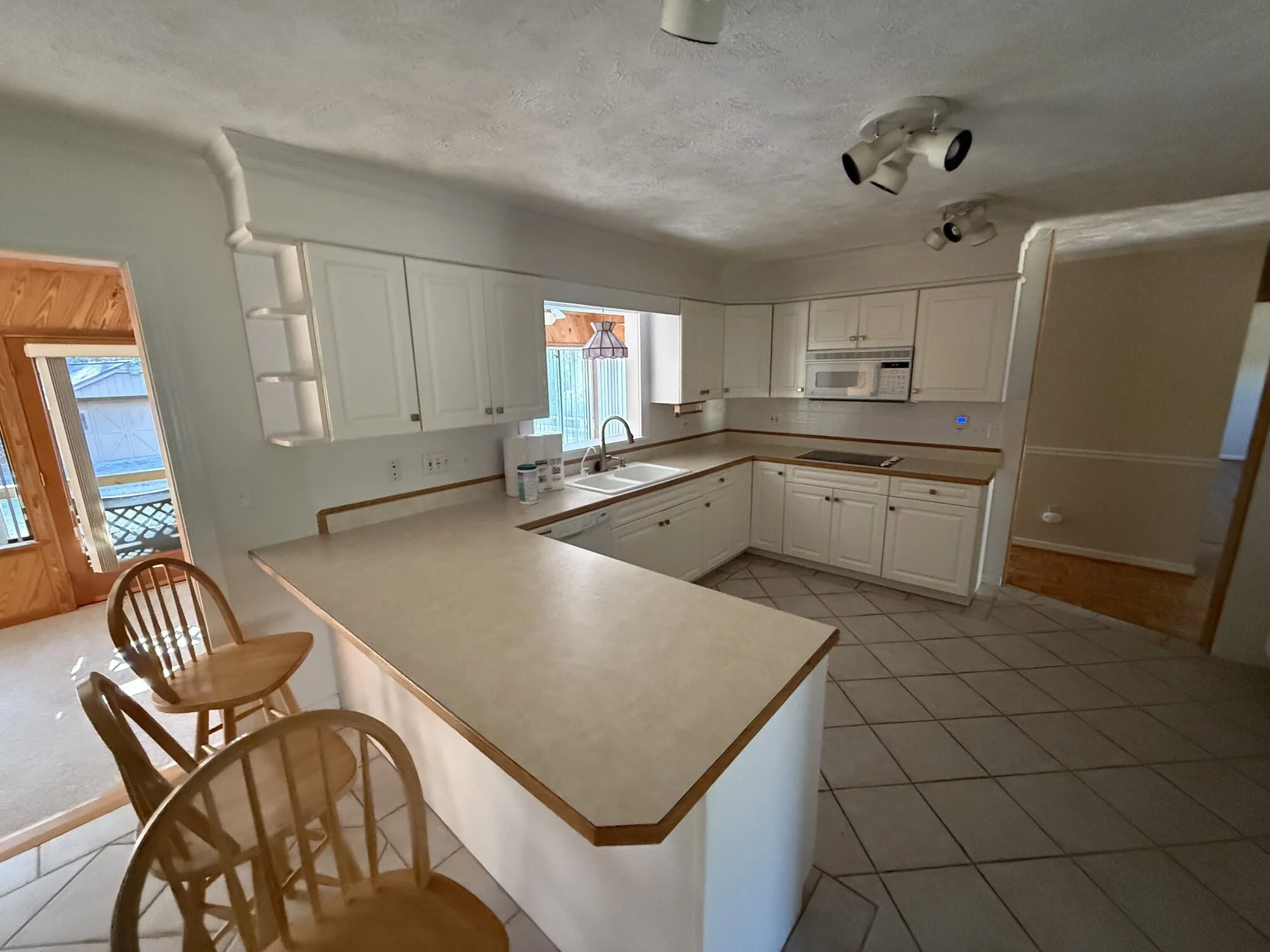 Before — the original kitchen with laminate counters, textured ceiling and tile floors