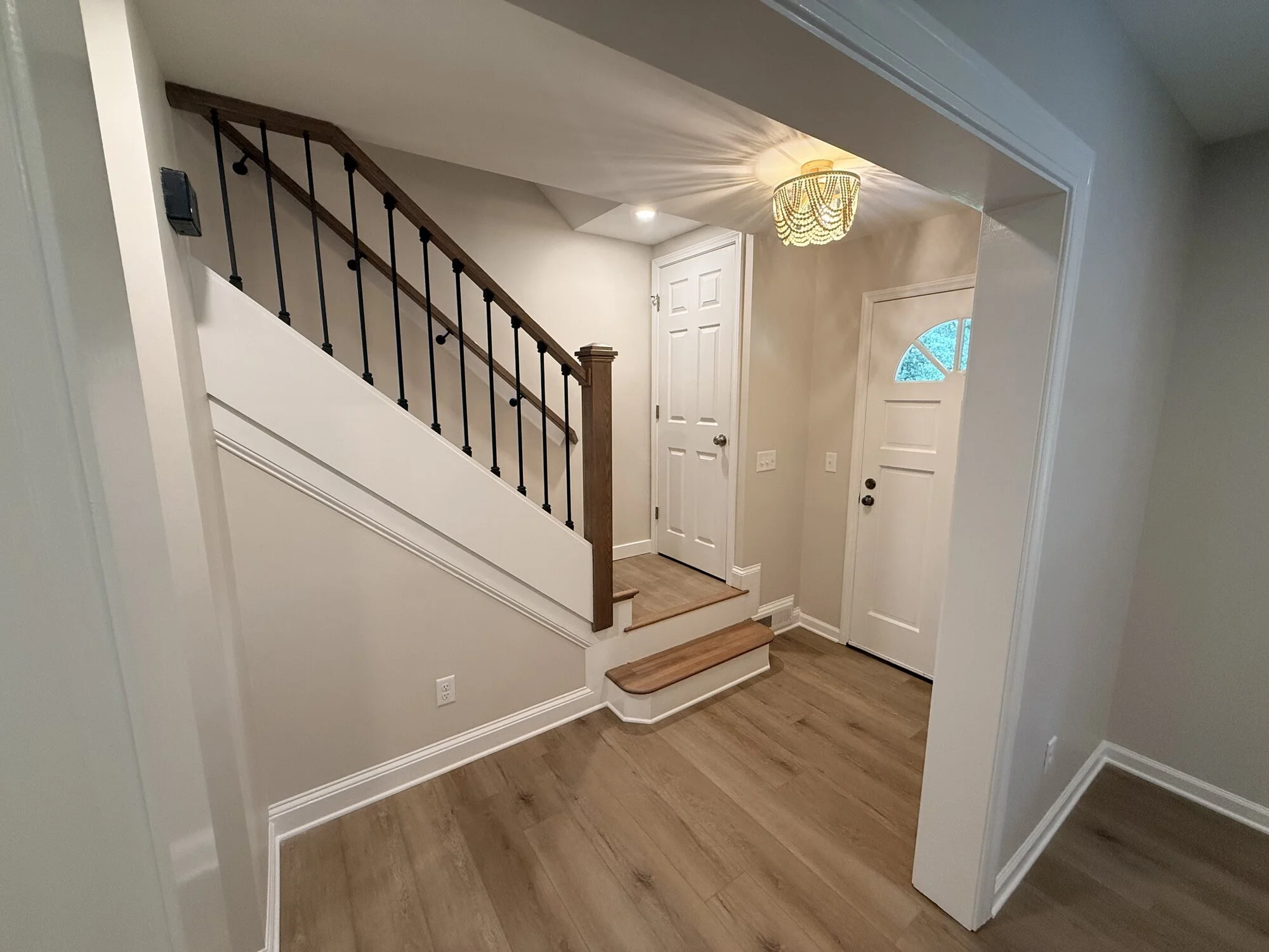 After — the opened-up entry with new flooring, fresh paint, and updated lighting