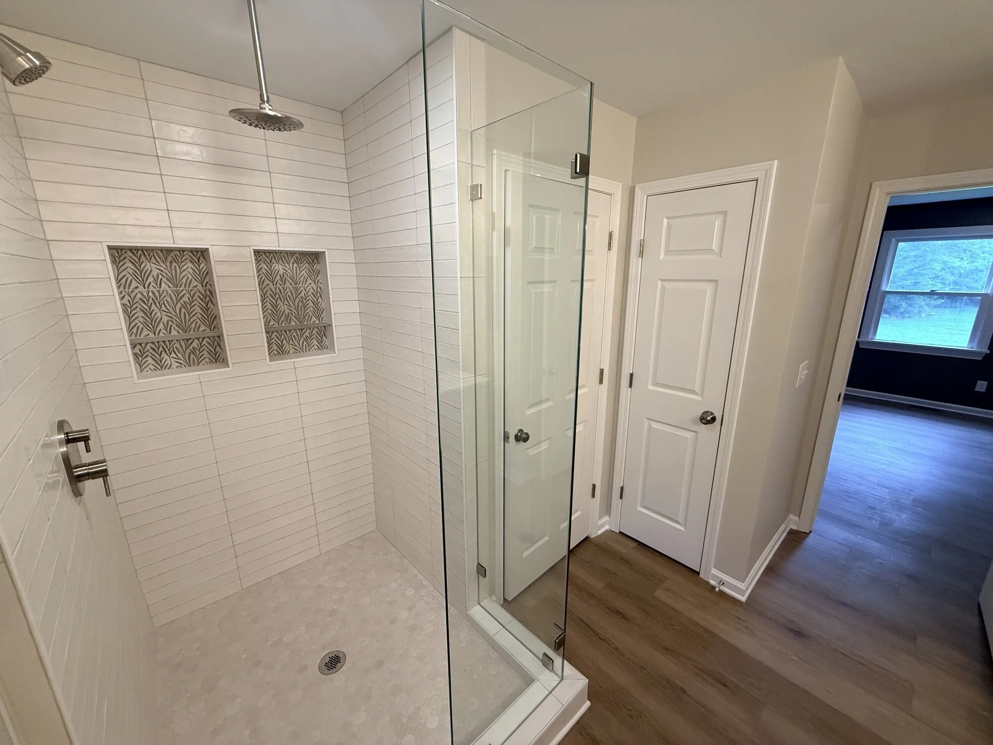 After — new walk-in shower with elegant tile, dual niches, rain head, and frameless glass