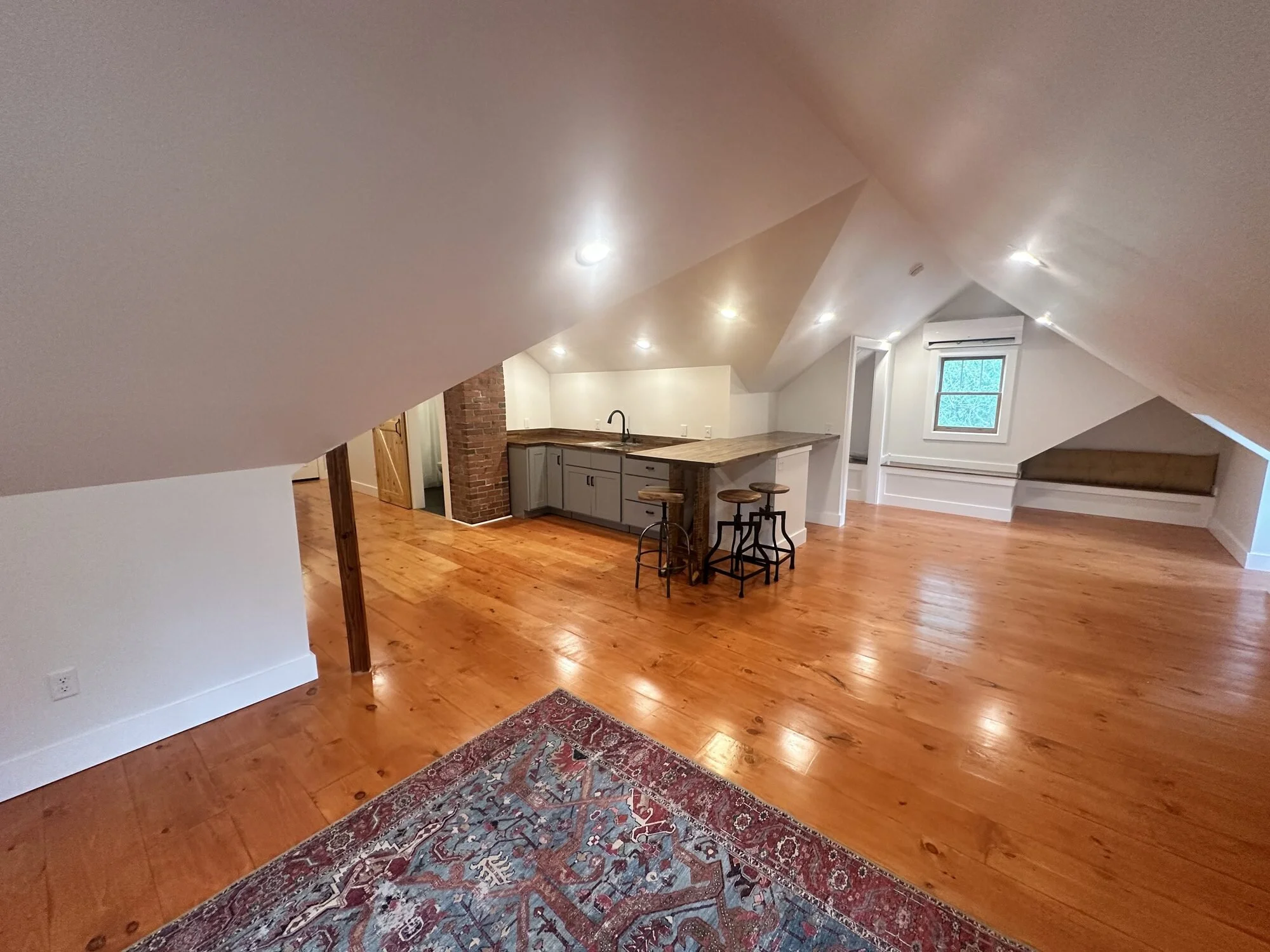 After — attic living area with refinished floors and window nook