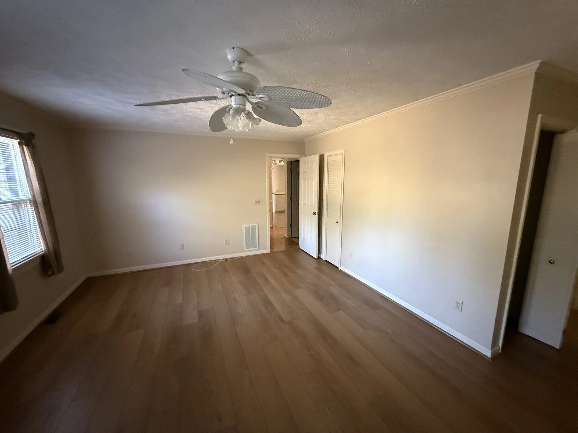 Before — Primary bedroom with dated flooring and fixtures prior to refinishing
