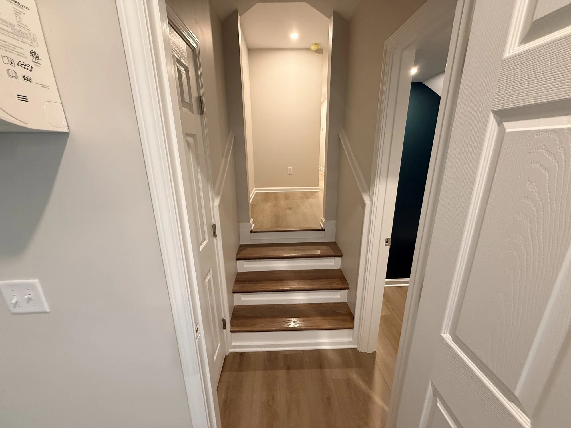 After — stair landing with new treads, paint, and trim leading to the upper level