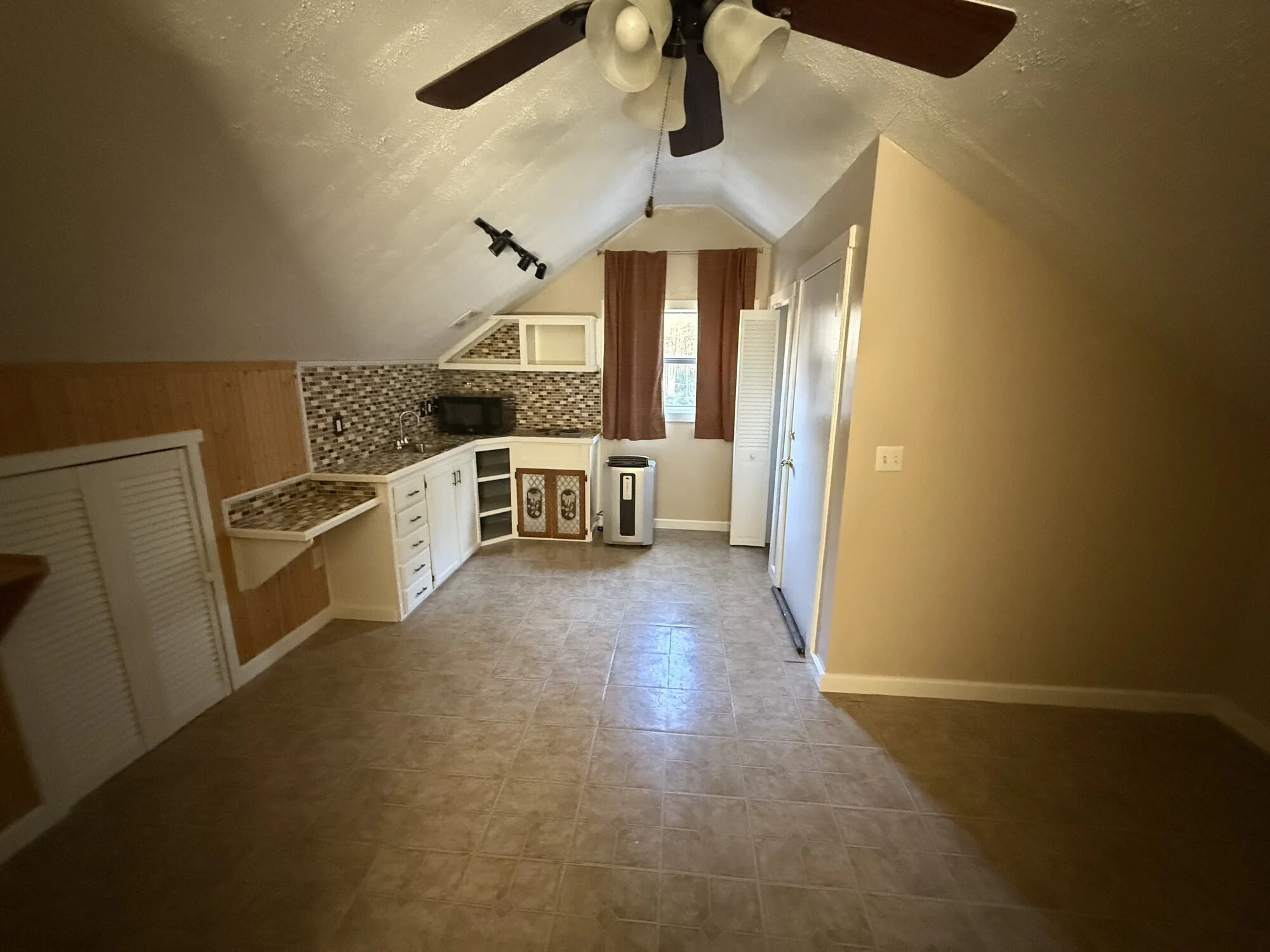 Before — upstairs bonus room with non permitted and dated kitchenette and worn linoleum 