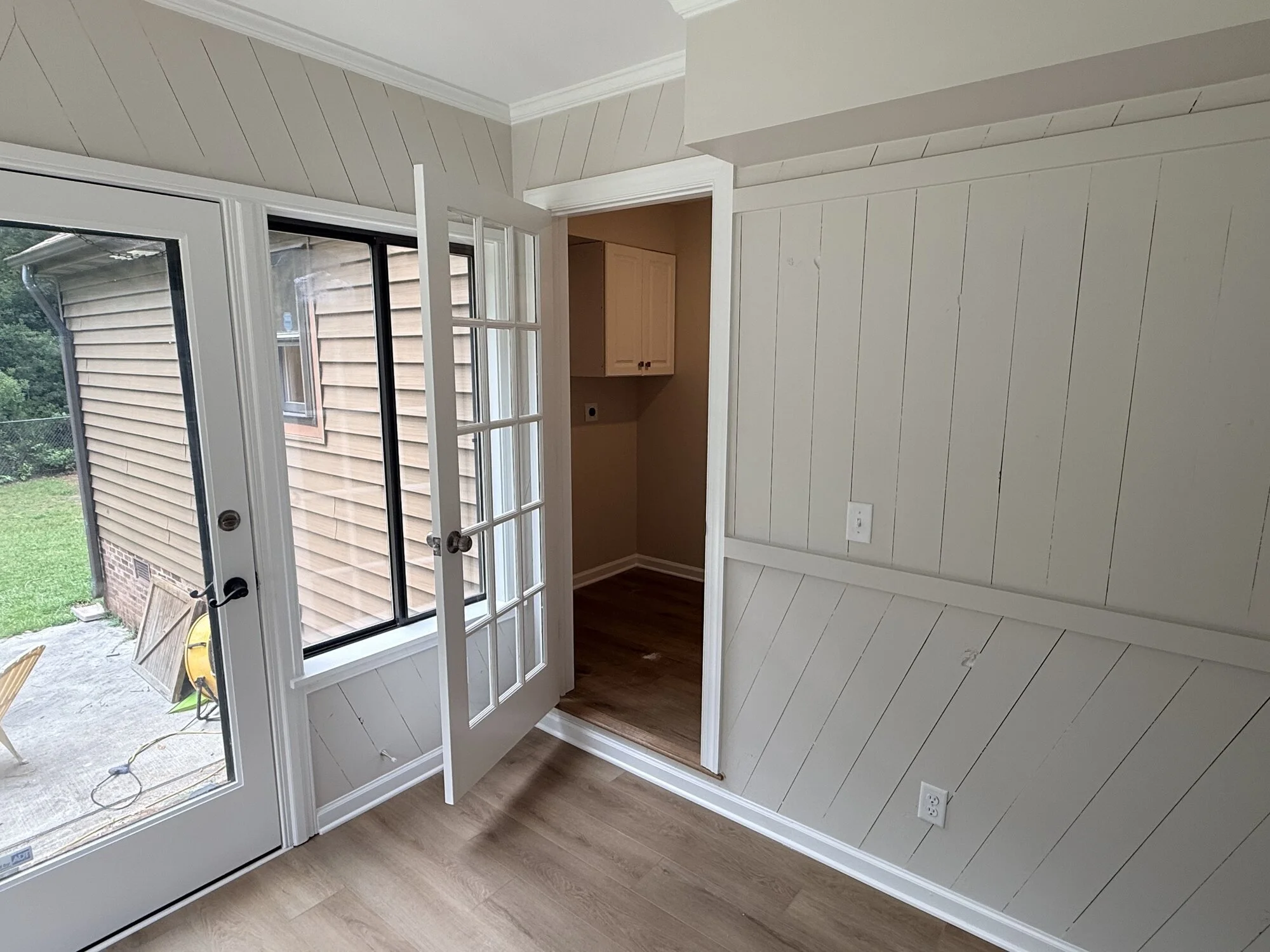 After — new glass panel door and freshly painted paneling opening to the backyard