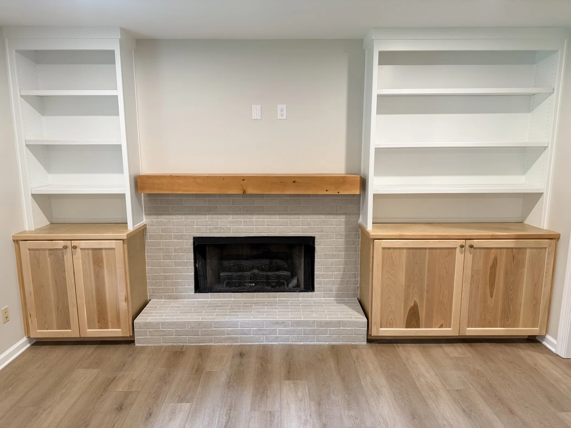 After — close-up of the custom built-in shelving and cabinet bases flanking the fireplace