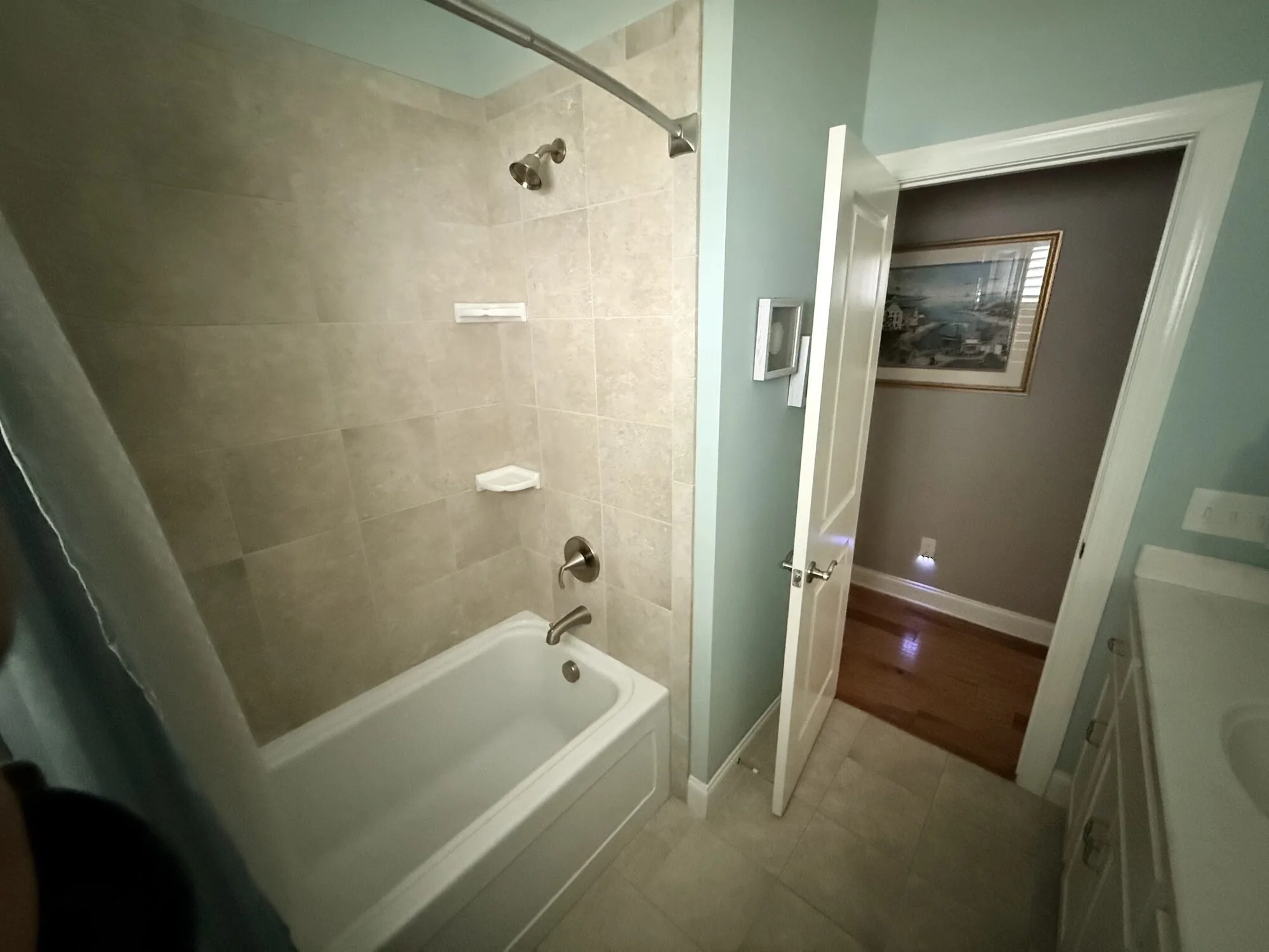 Before — original tub and shower combo with dated tile surround