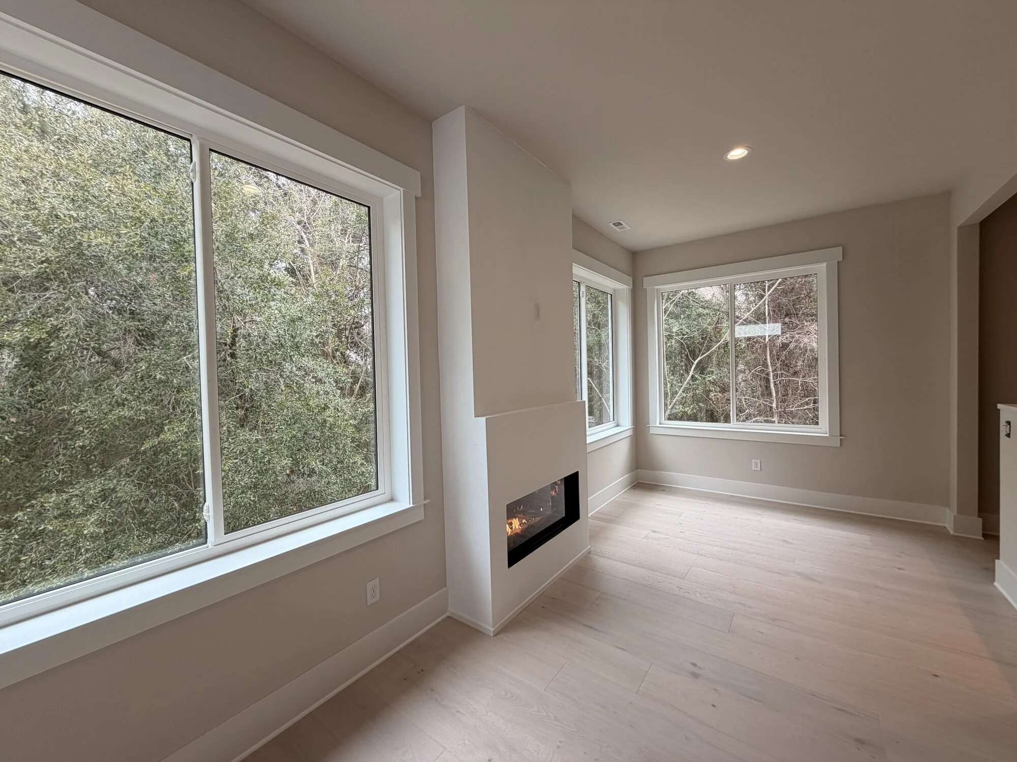 After — corner view of fireplace and treetop views in the new living space