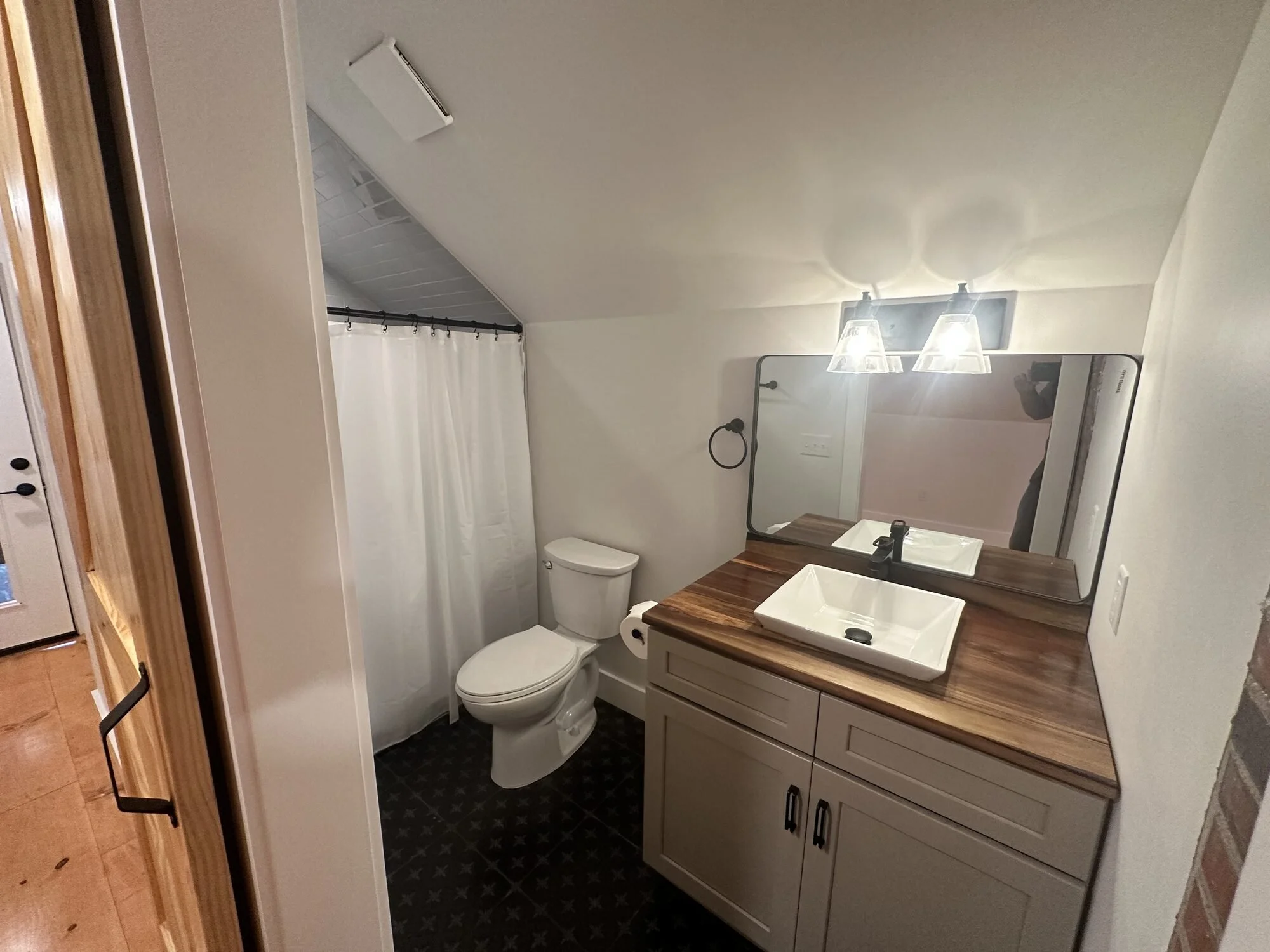 After — butcher block vanity with vessel sink, black fixtures, and mosaic tile floor