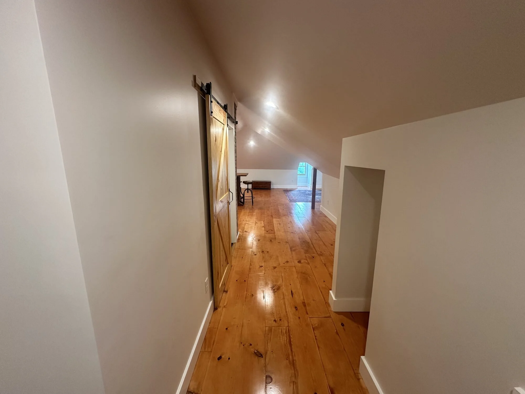 After — finished hallway with sliding barn door and rustic wood floors