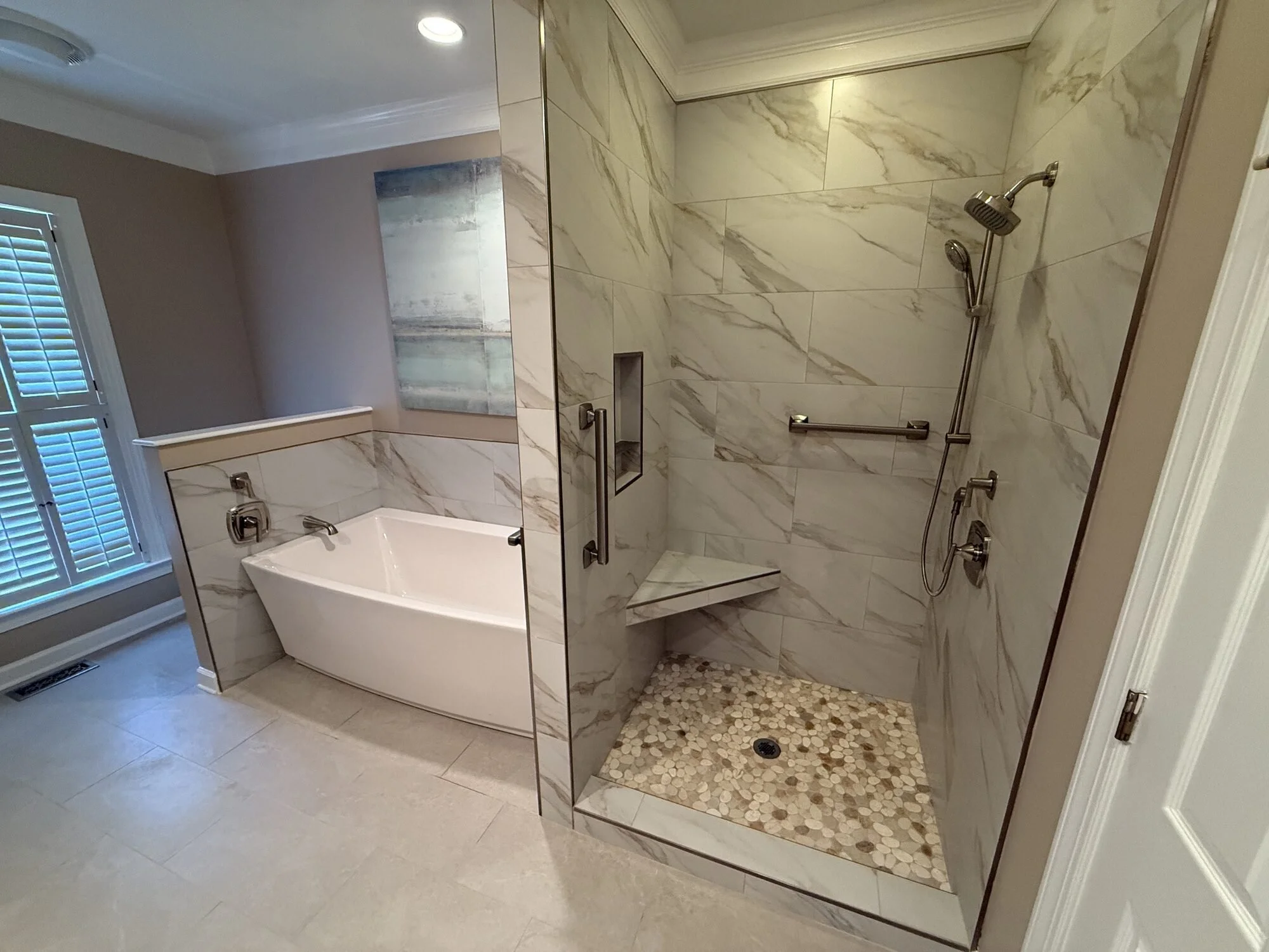 After — the rebuilt walk-in shower in marble-look tile with frameless glass and bench