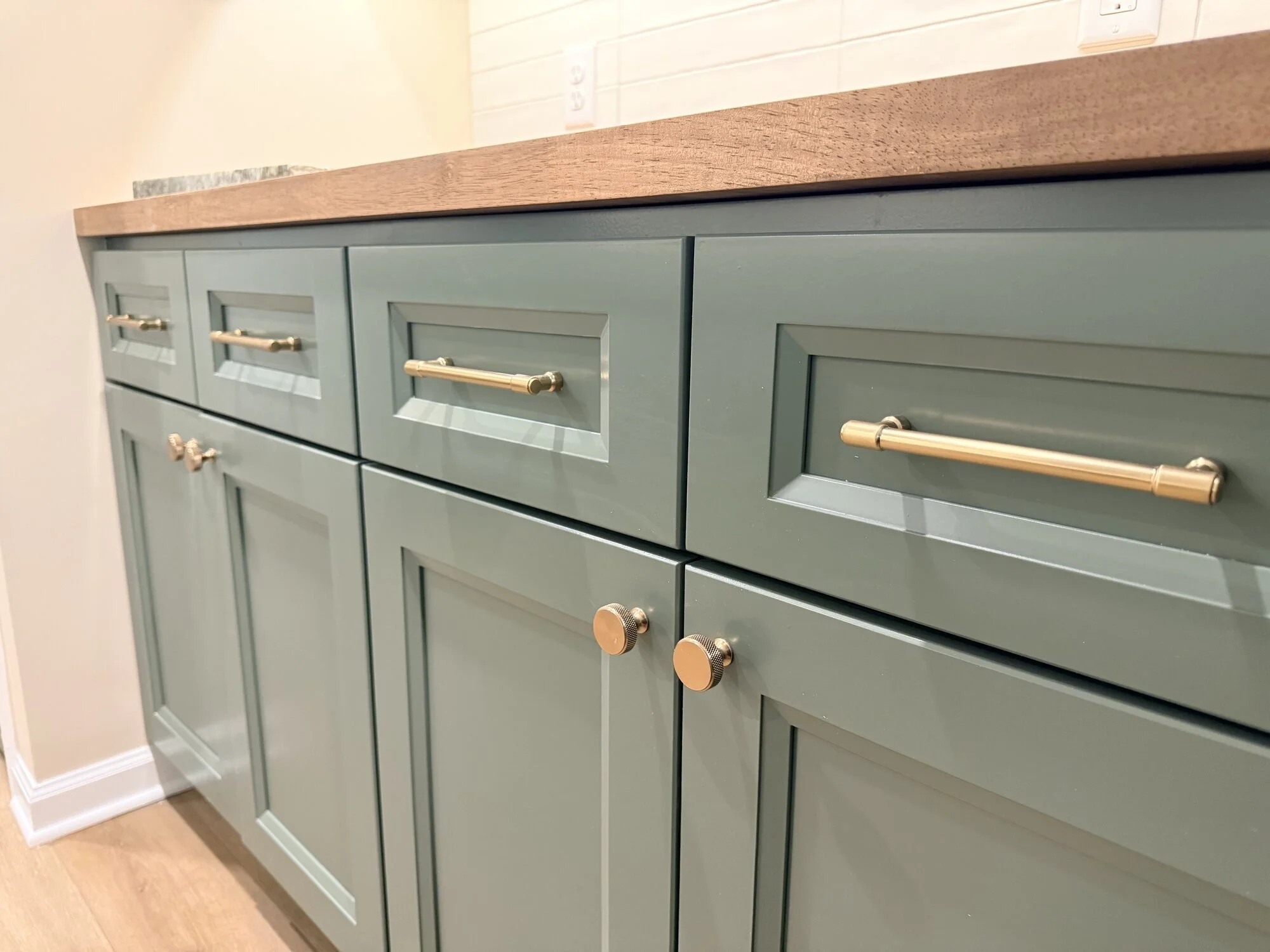 After — cabinet detail: Lush green, butcher block, and brass hardware