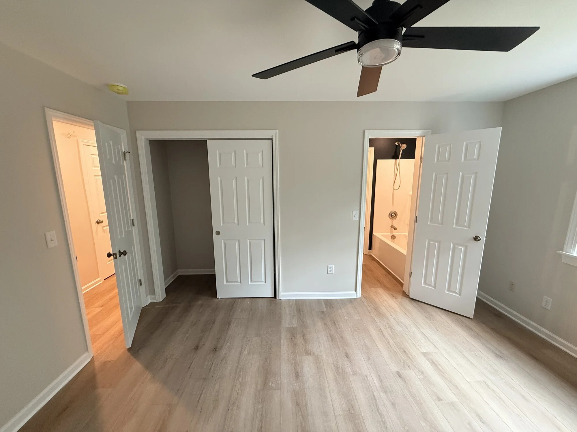 After — bedroom refreshed top to bottom with new doors, floors, and paint with added Jack and Jill bathroom entrance