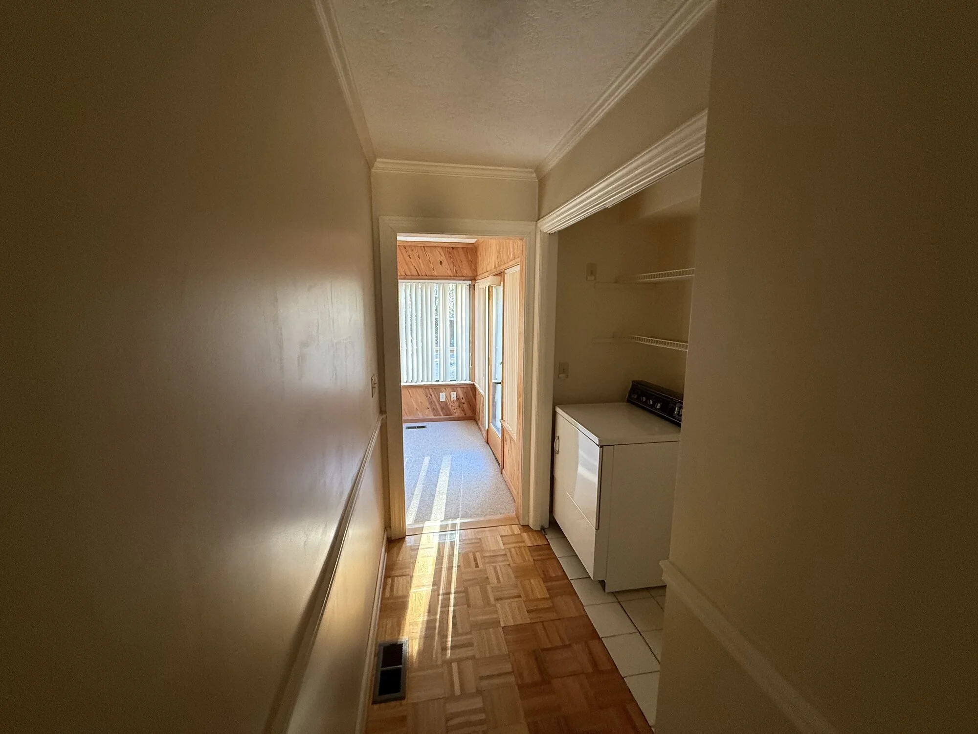 Before — dark laundry passage with dated tile and paneling