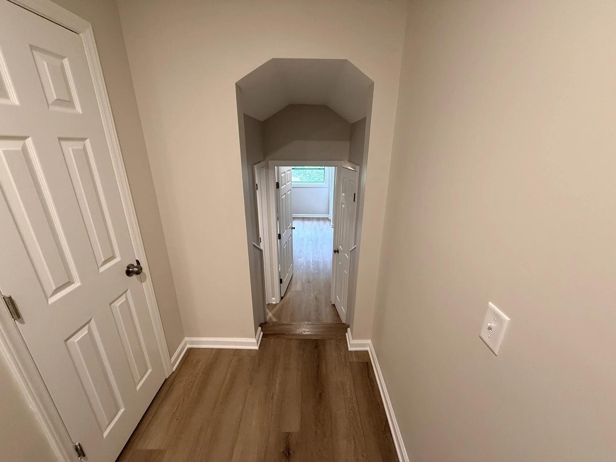 After — arched hallway refreshed with new flooring, doors, and paint