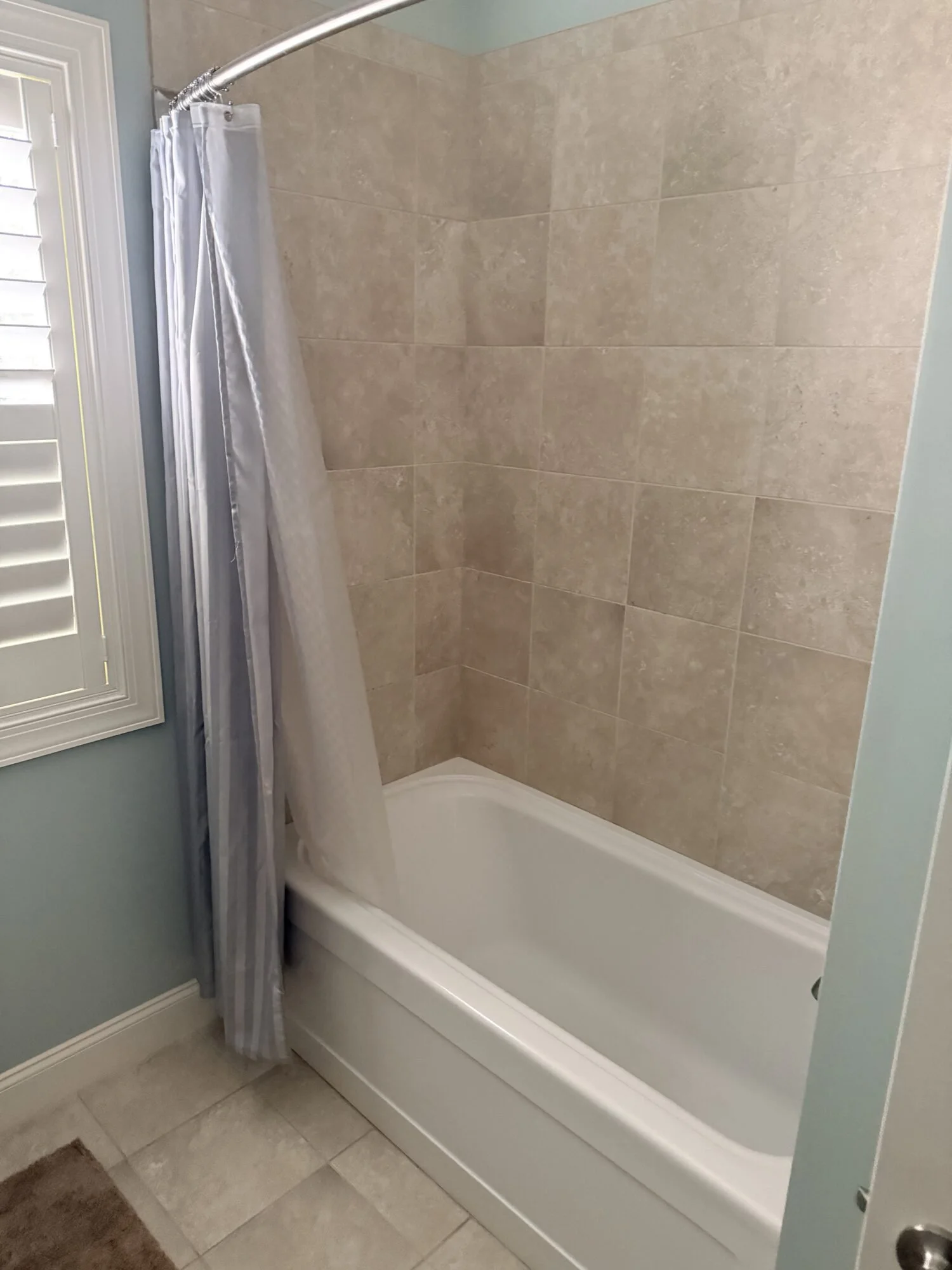 Before — existing tub and tile surround with shower curtain