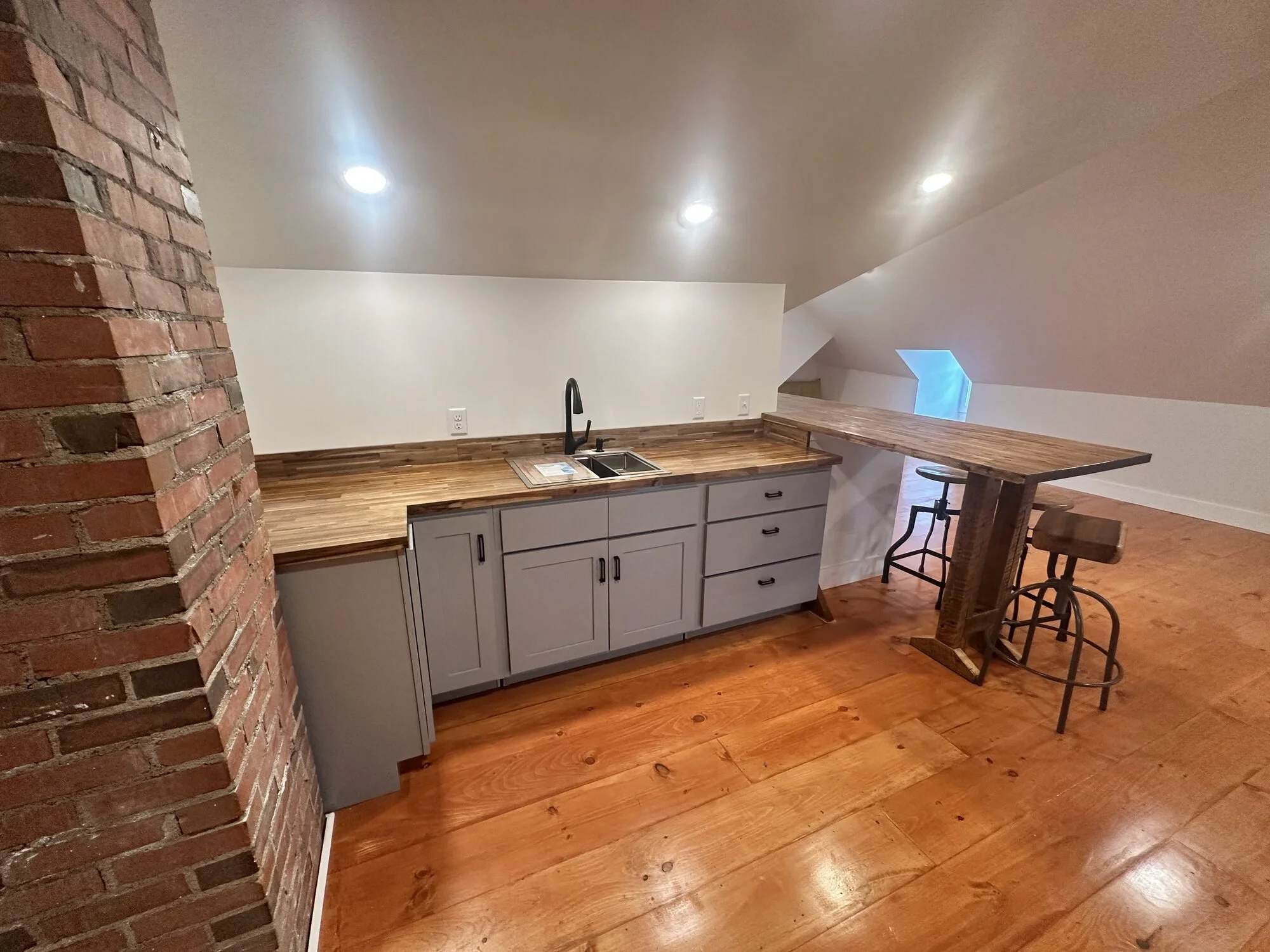 After — kitchenette and seating built beside the original exposed brick chimney