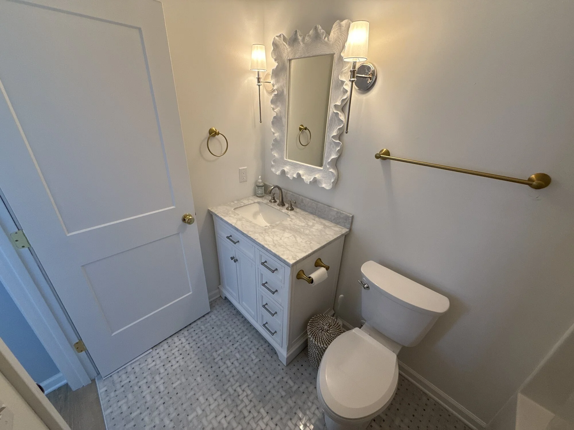 After — bathroom vanity with sconce lighting and framed mirror