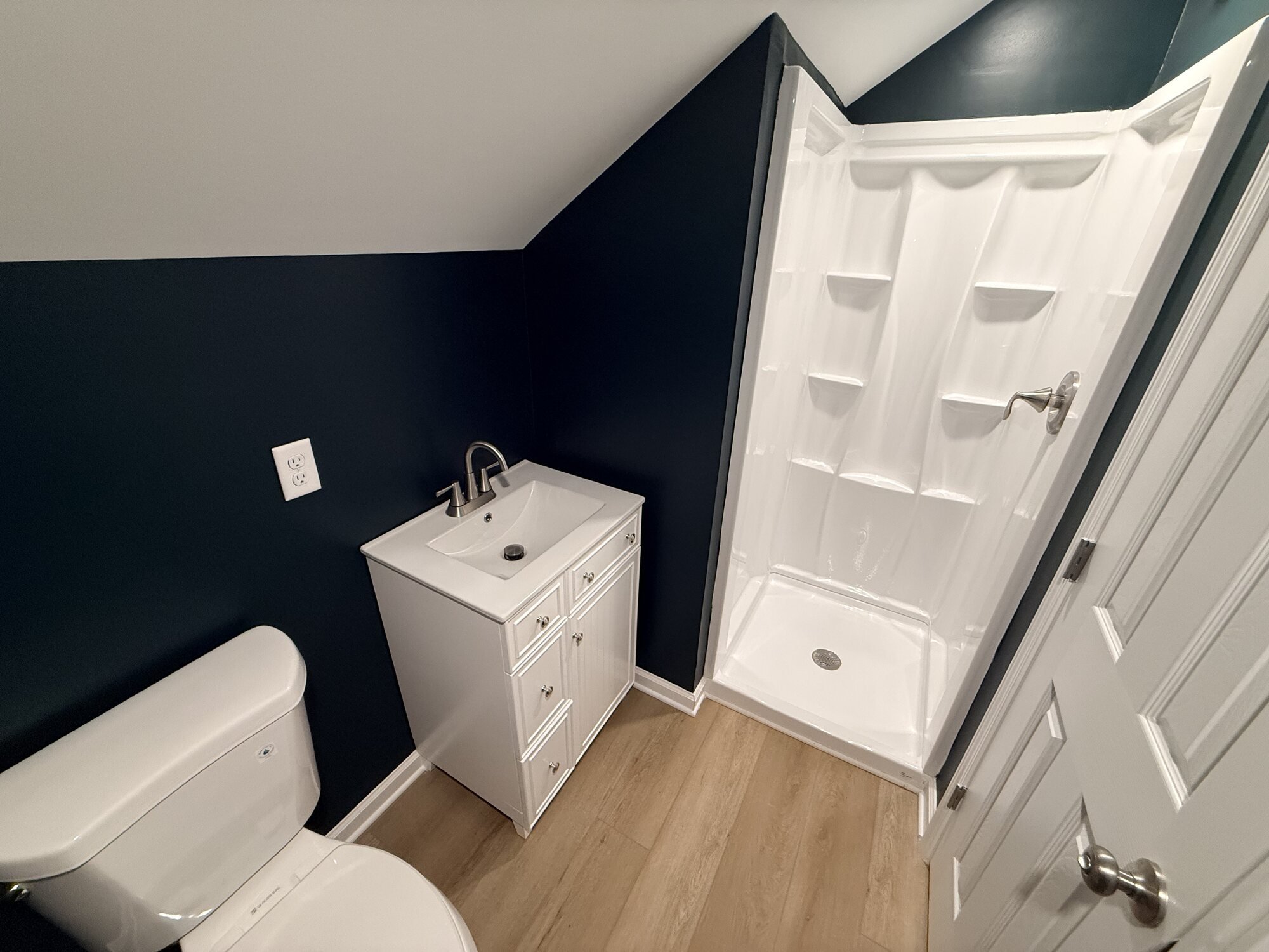 After — upstairs bath reworked with navy accent wall, new vanity, shower, and flooring