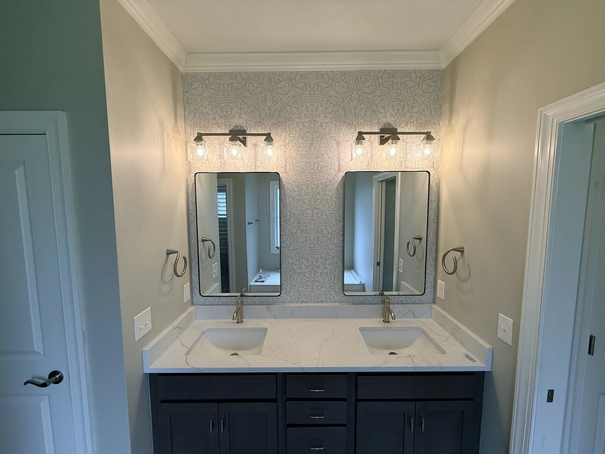 After — remodeled double vanity with quartz counters, dual framed mirrors, and updated sconce lighting