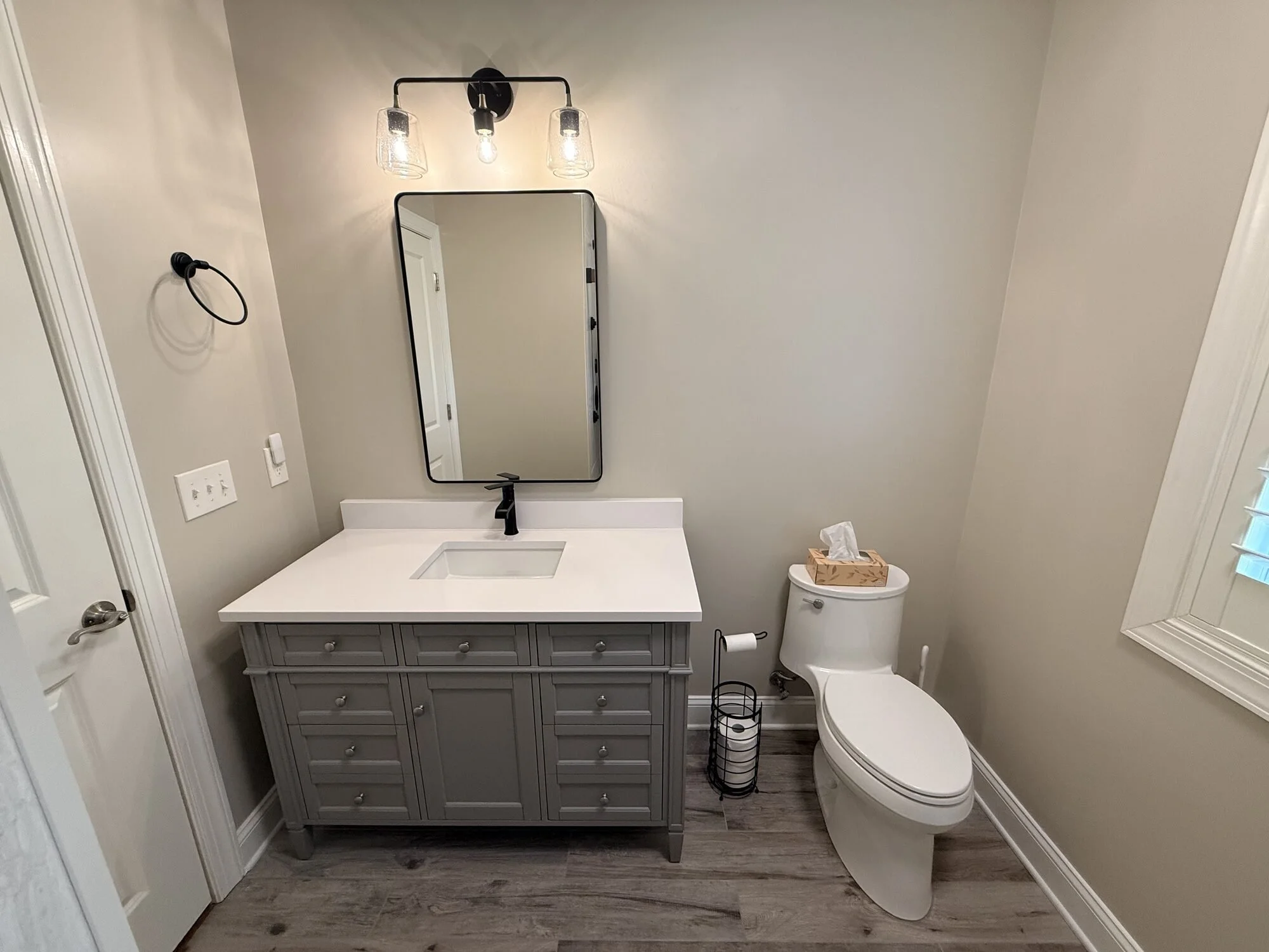 After — new gray vanity with quartz top, matte black fixtures, and framed mirror