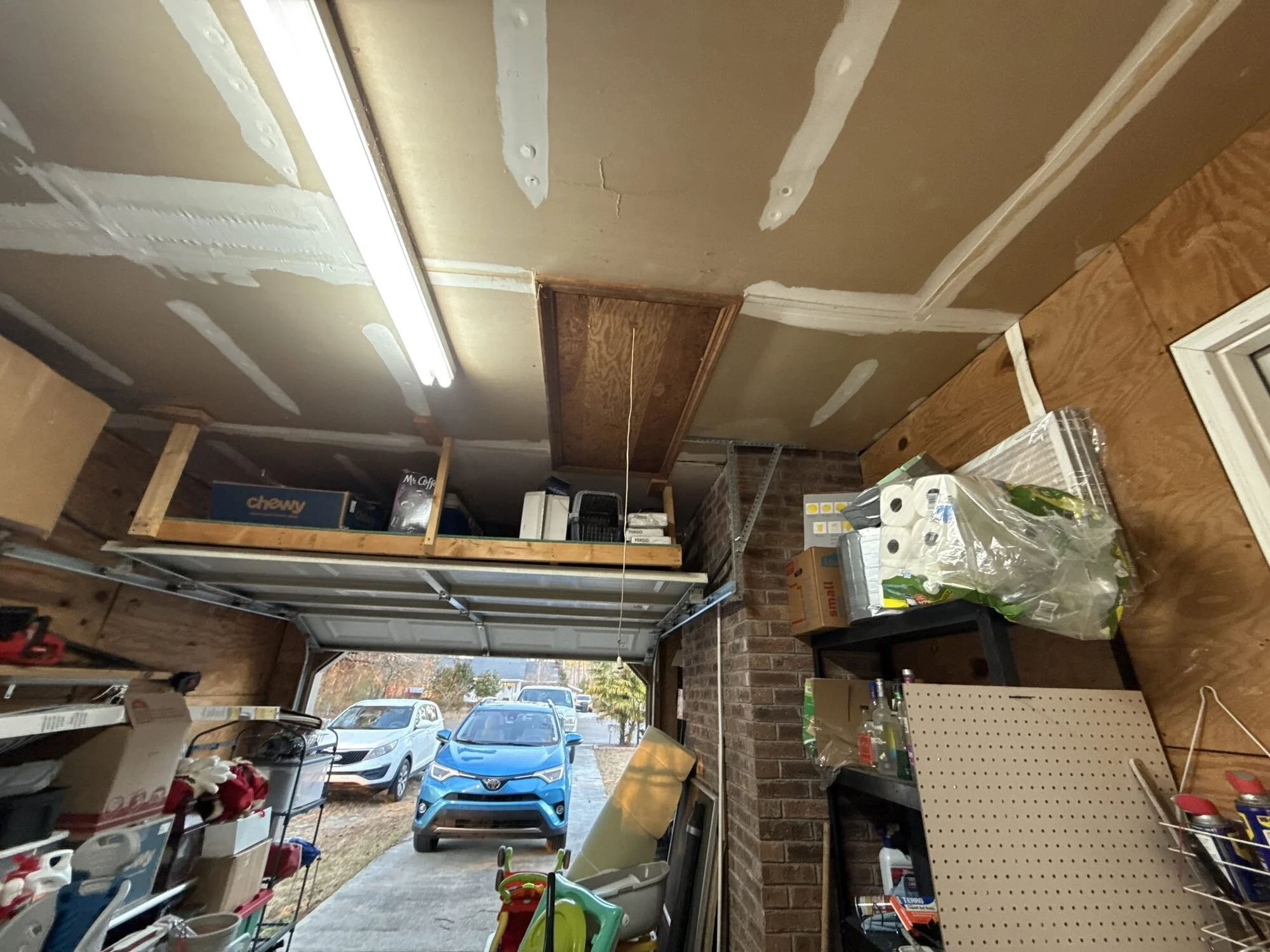 Before — the garage in full storage mode, framing and shelves exposed