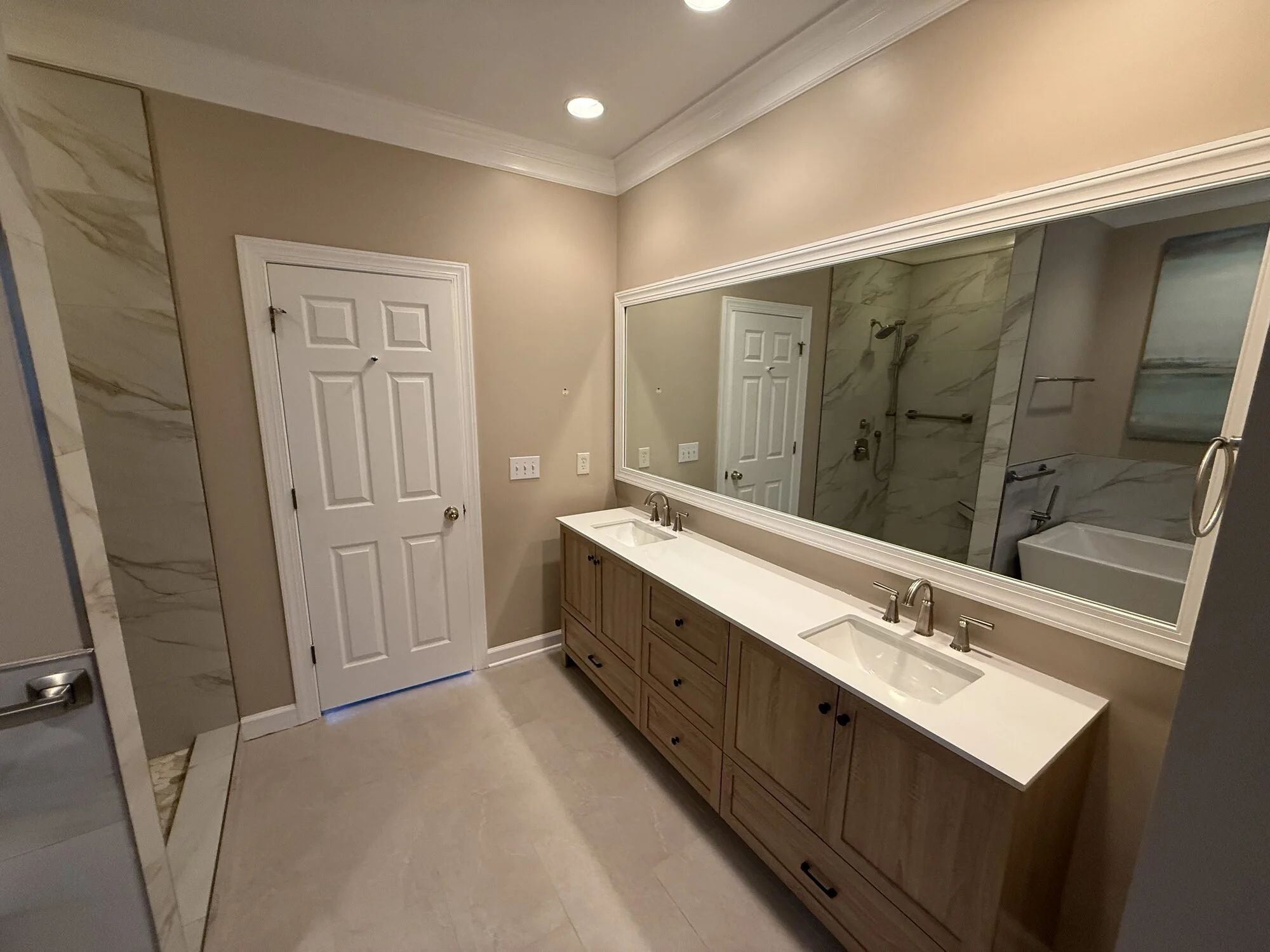 After — new furniture-grade double vanity with white counters, framed mirror, and sconces