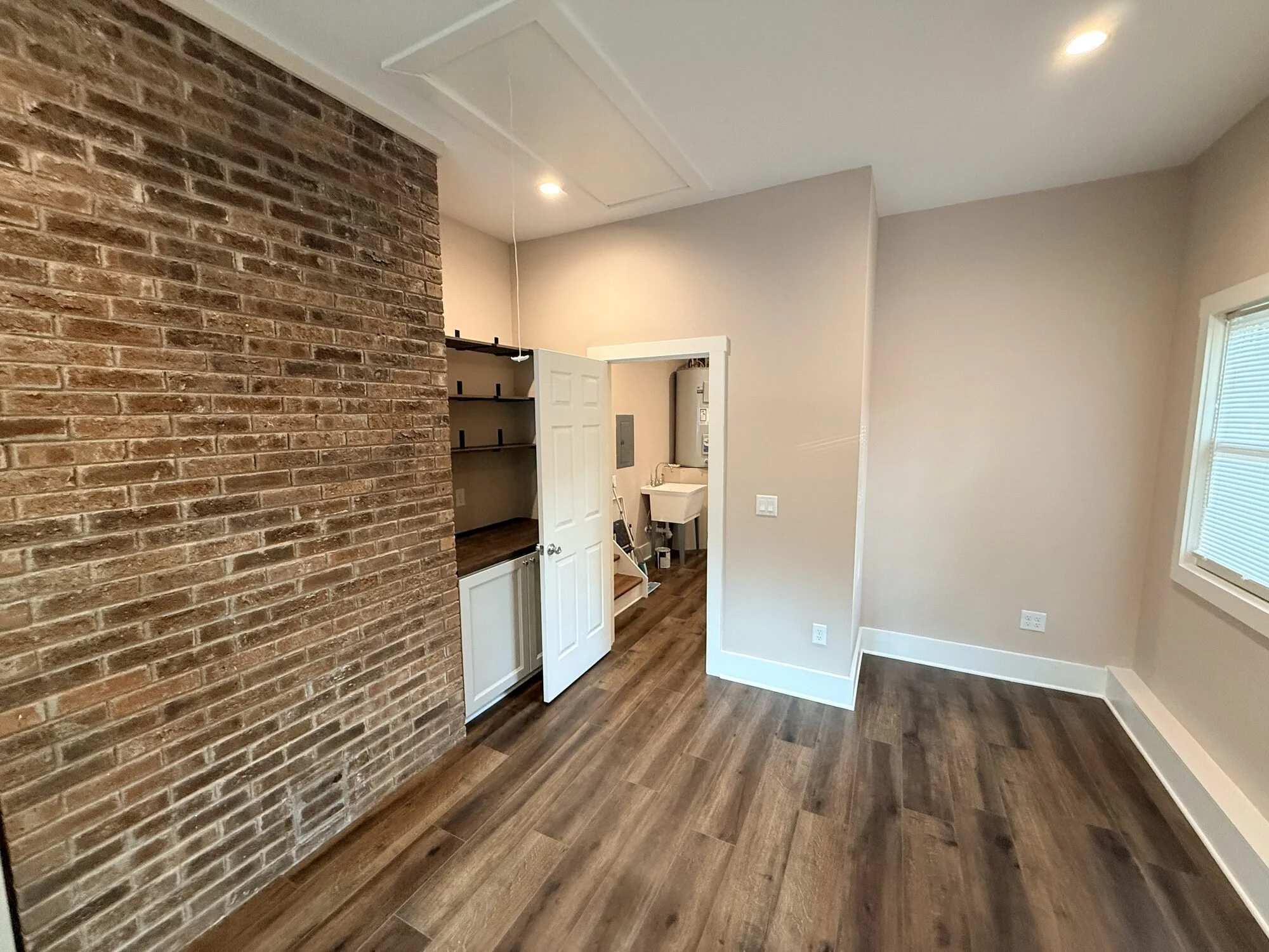 After — brick accent wall framing the doorway to the new utility area