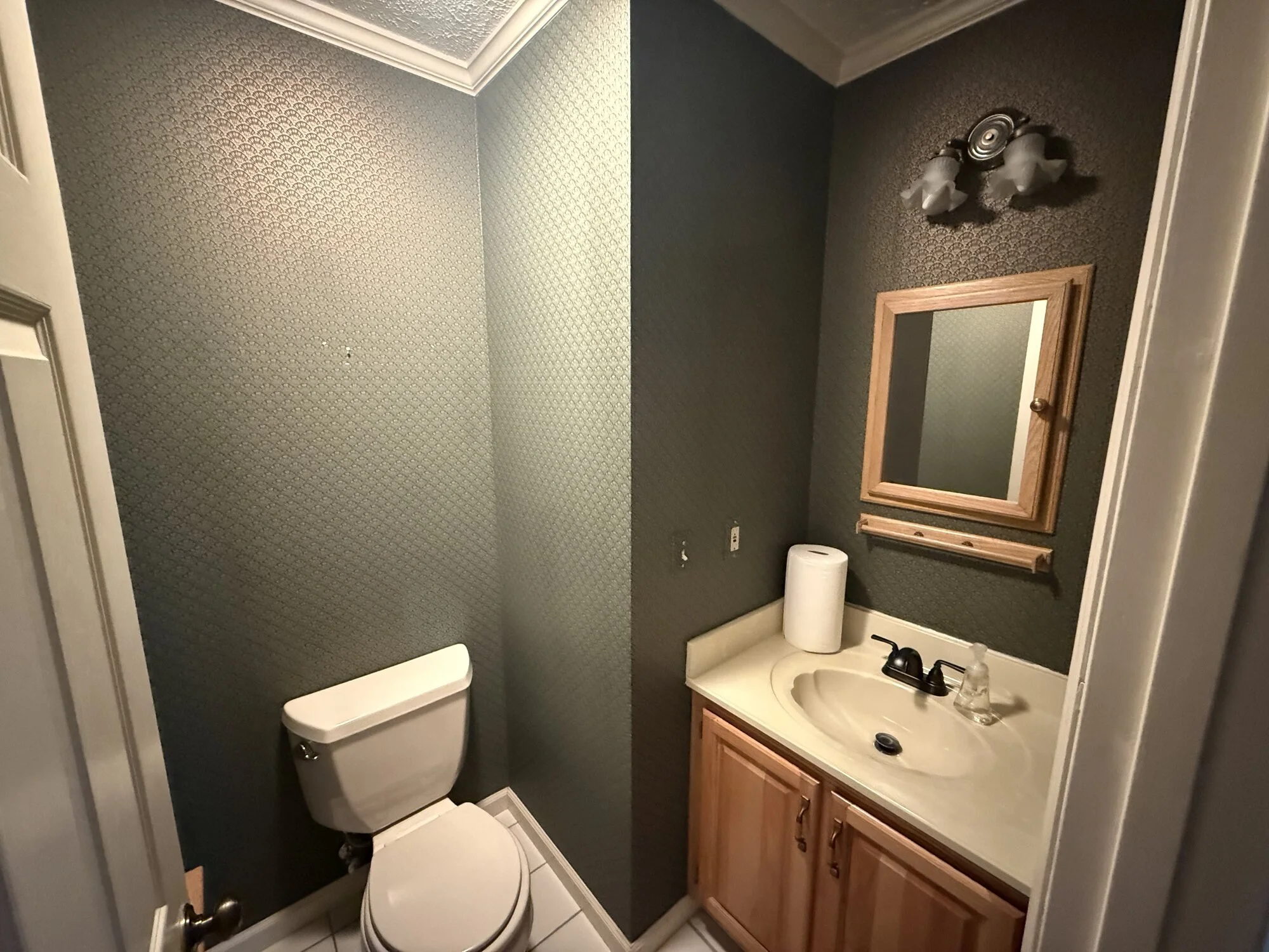 Before — powder room with dated oak vanity and dark walls