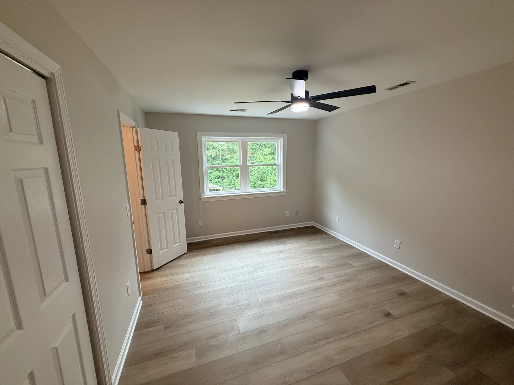 After — upstairs second bedroom updated with new flooring, windows, fresh paint, and ceiling fan