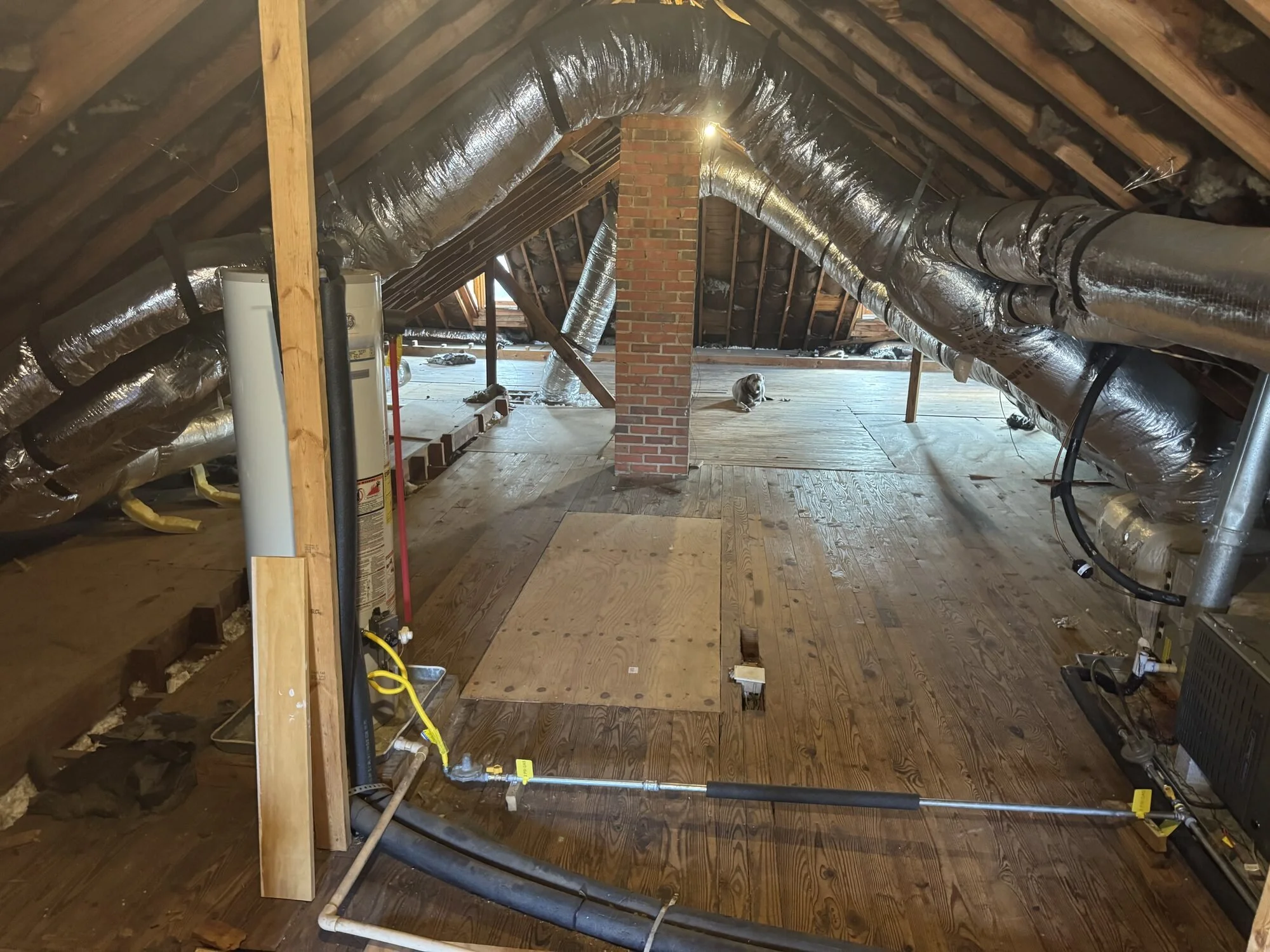 Before — plumbing roughed in beside the brick chimney in the raw attic