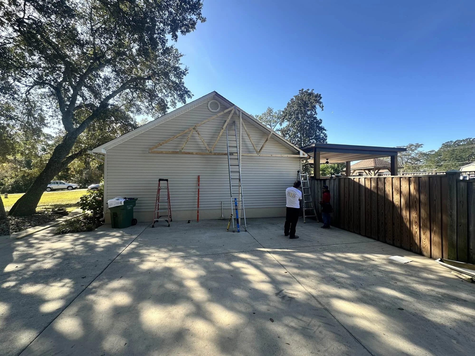 Before — the bare slab and gable end where the carport would land