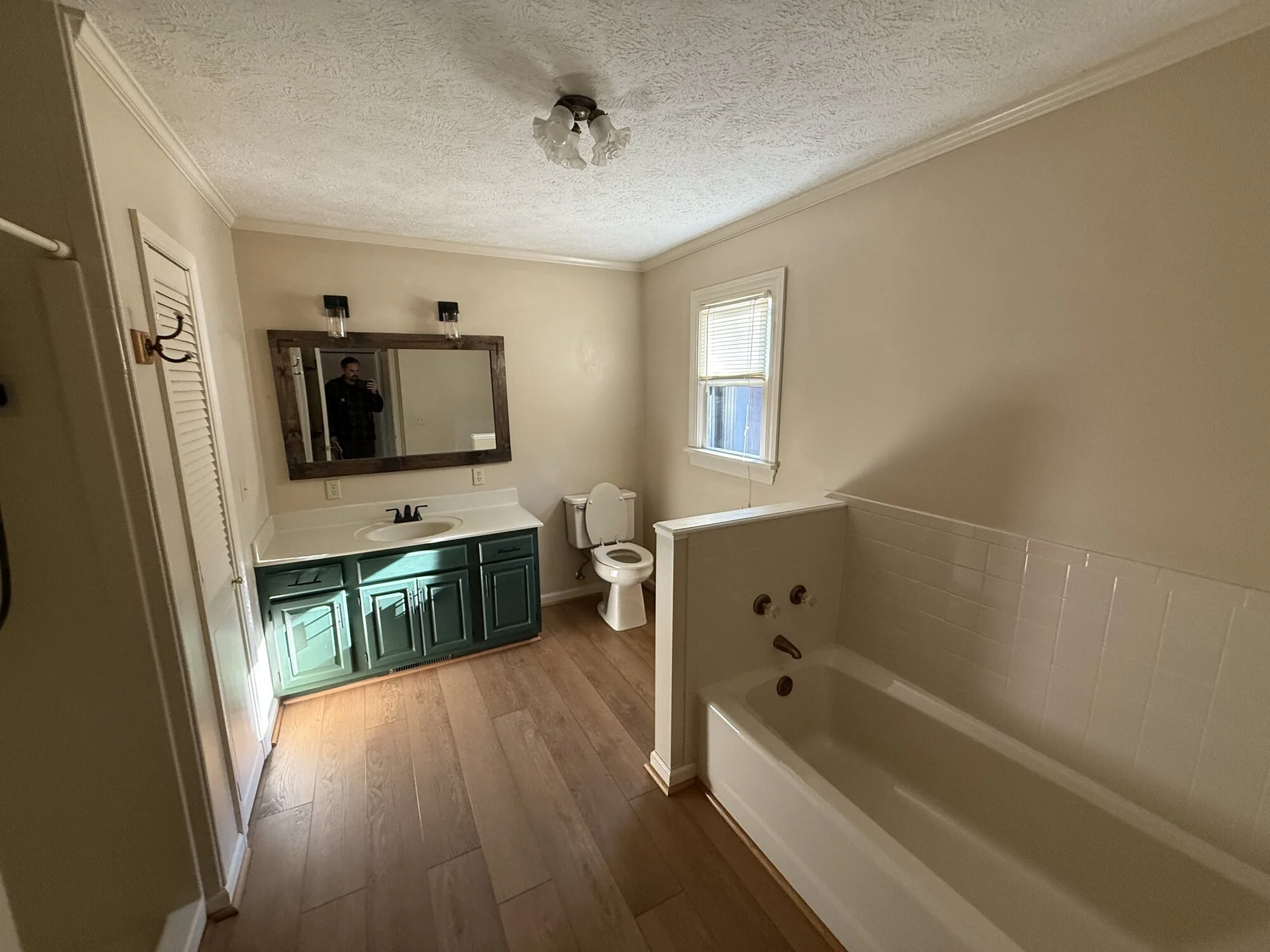 Before — primary bath with dated tub deck and green vanity