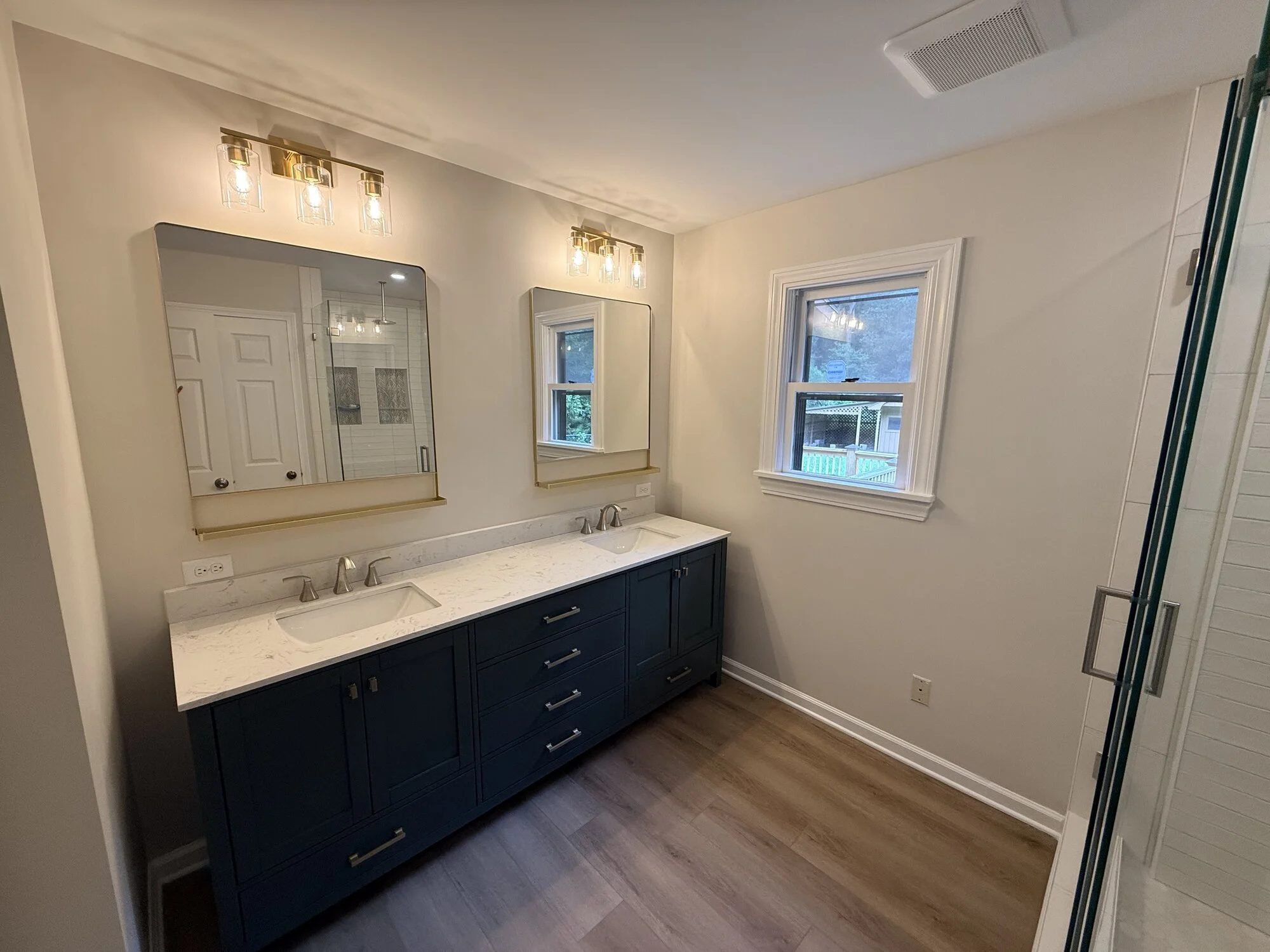 After — the new double vanity wall with dual mirrors, light fixtures, and natural light