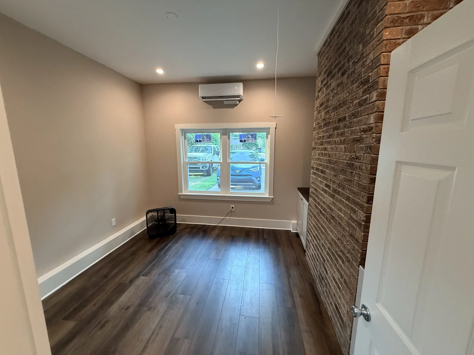 After — finished office space with exposed brick accent wall and new laminate wood flooring