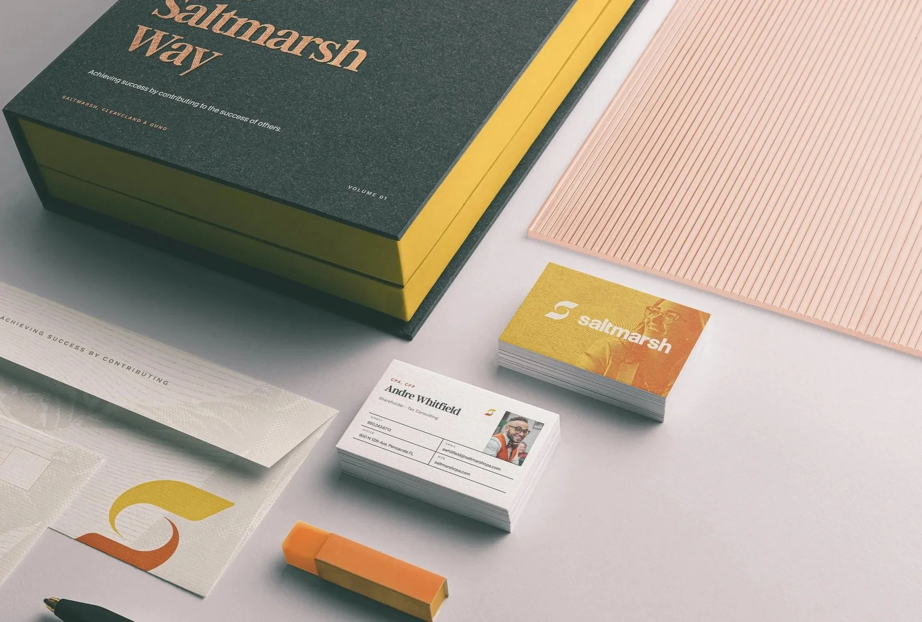 A printed brand identity laid out on a pale grey surface: a dark green and yellow presentation box reading Saltmarsh Way, gold foil business cards, printed stationery and a pink textured sheet.