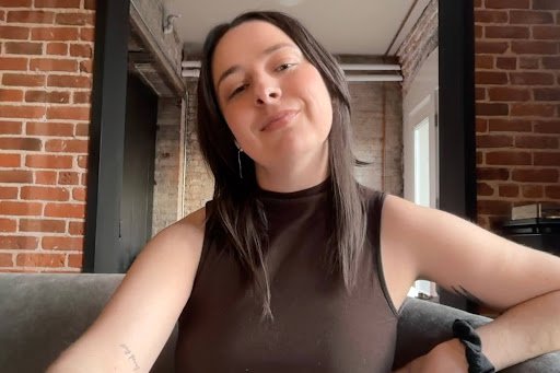 Person smiling outdoors with green foliage background