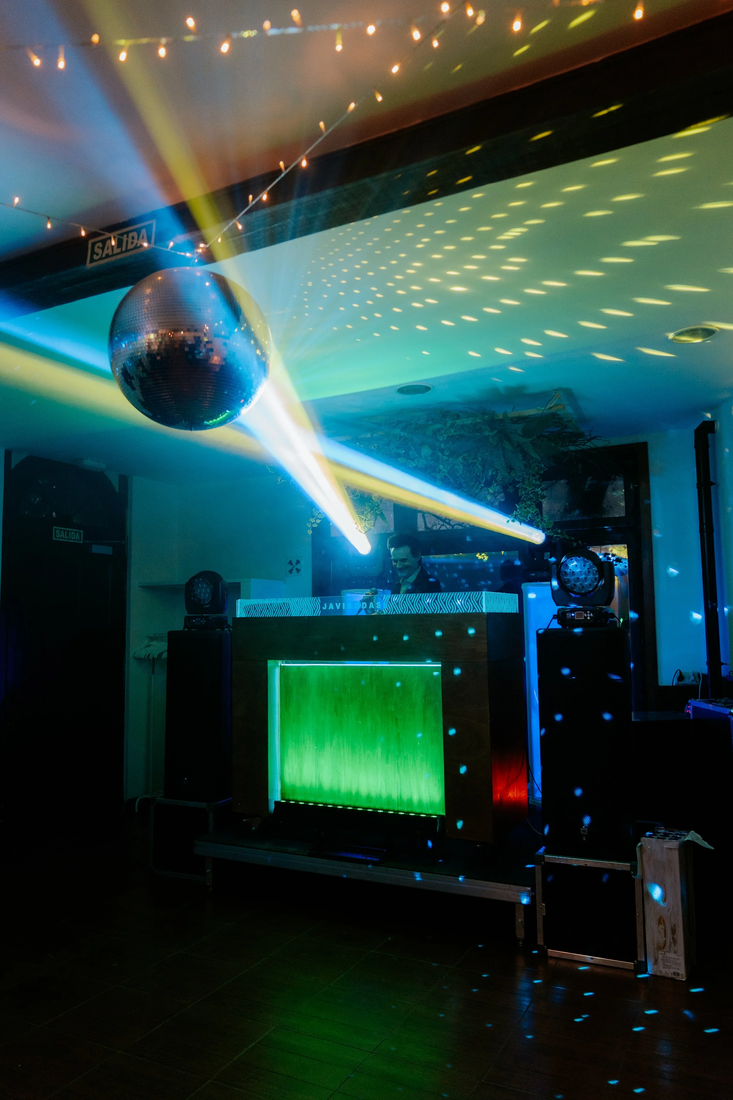 Pista de DJ con luces y bola de discoteca en una fiesta o club, ambiente oscuro con efectos de iluminación.