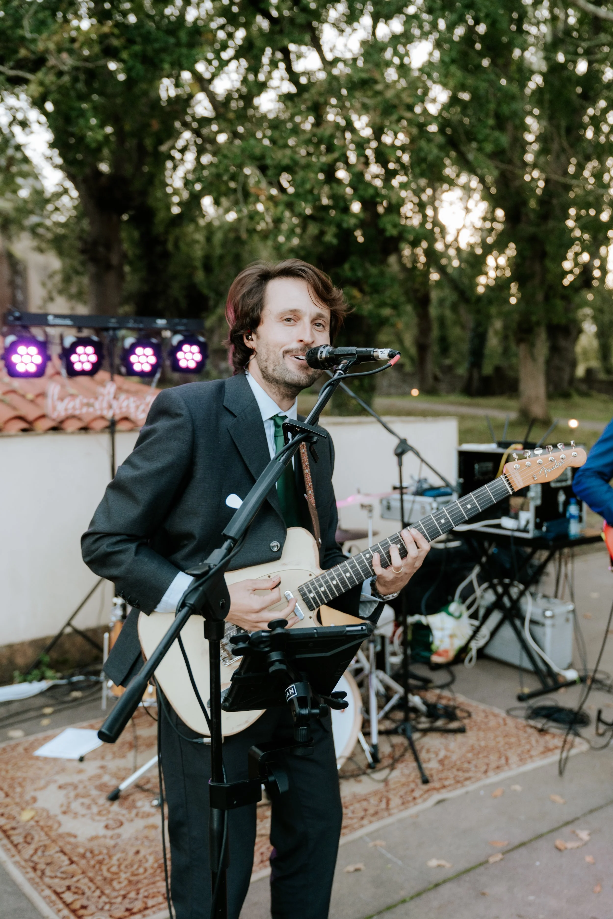 Hombre tocando la guitarra y cantando en un escenario al aire libre durante una actuación musical.