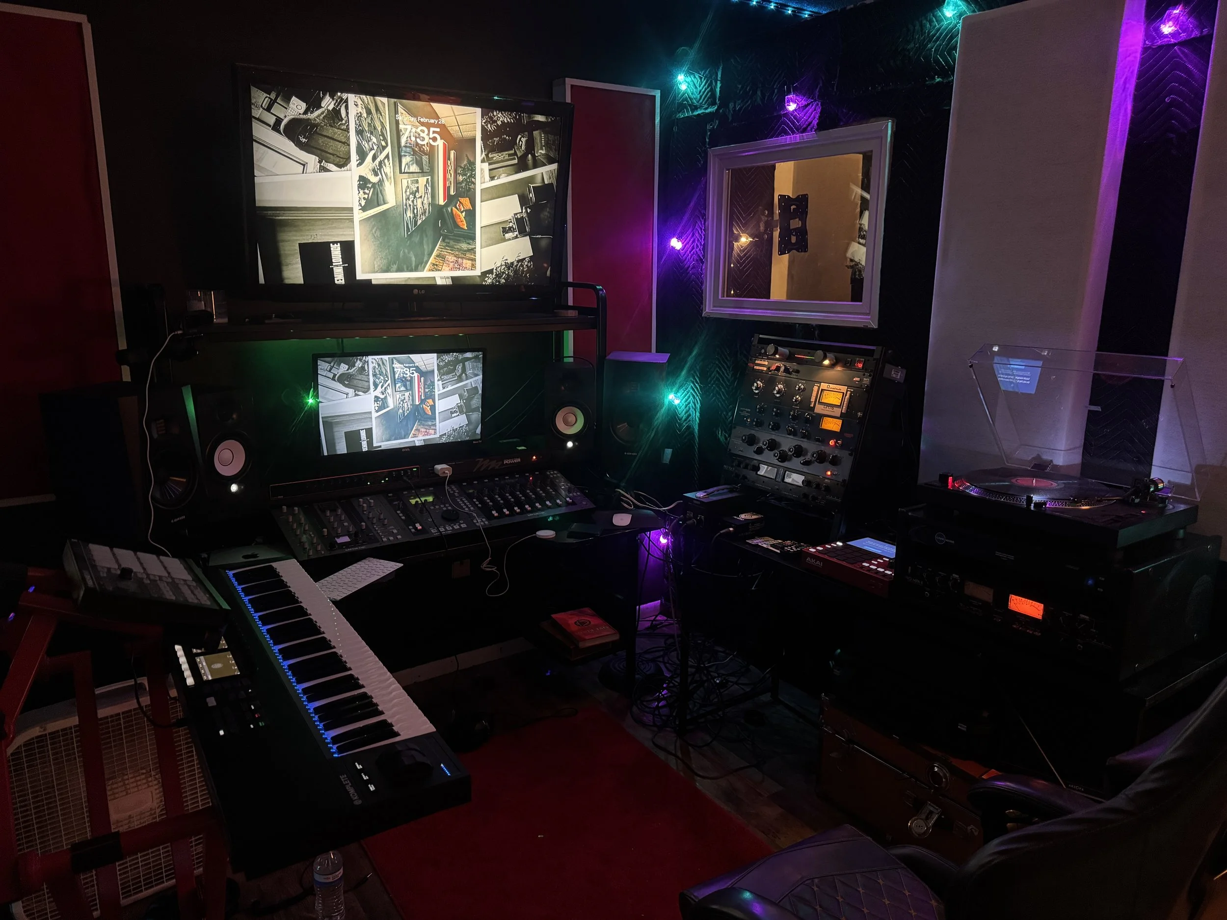 A cozy corner in a music-themed lounge featuring framed album covers and posters of musicians on dark wall decor. There is a red leather sofa, a small wine display cabinet, and wall lighting creating a warm atmosphere.