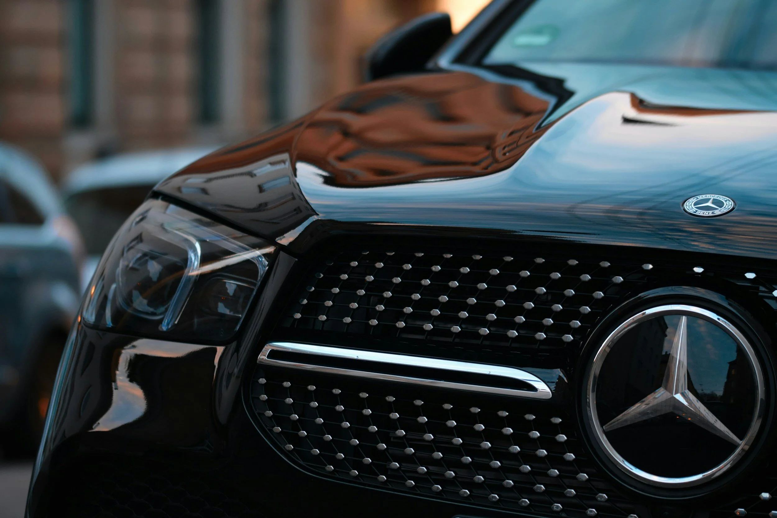 Close-up of the front grille and headlight of a black Mercedes-Benz car.