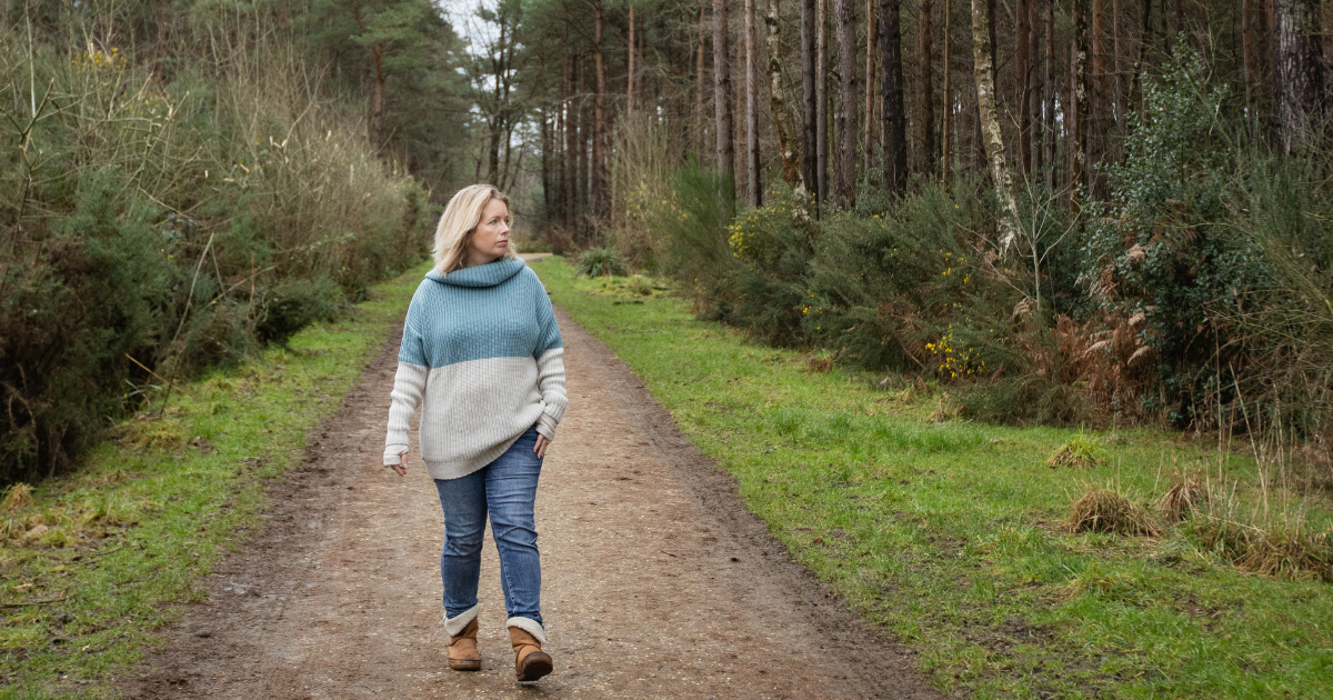 Woman walking along woodland path in Berkshire looking to the side