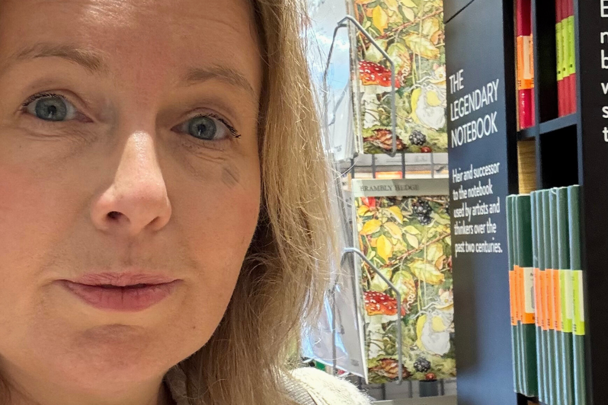 Midlife woman browsing journals in a bookshop.
