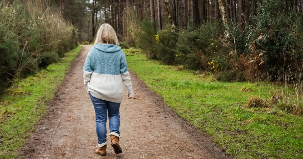 Woman walking along a woodland path in Berkshire during a reflective walk