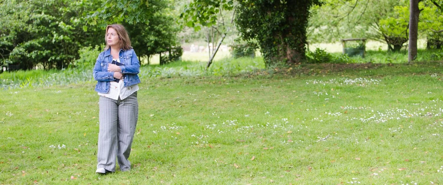 Sarah walking through a peaceful green space, reflecting on slowing down and creating a calmer everyday life in midlife.