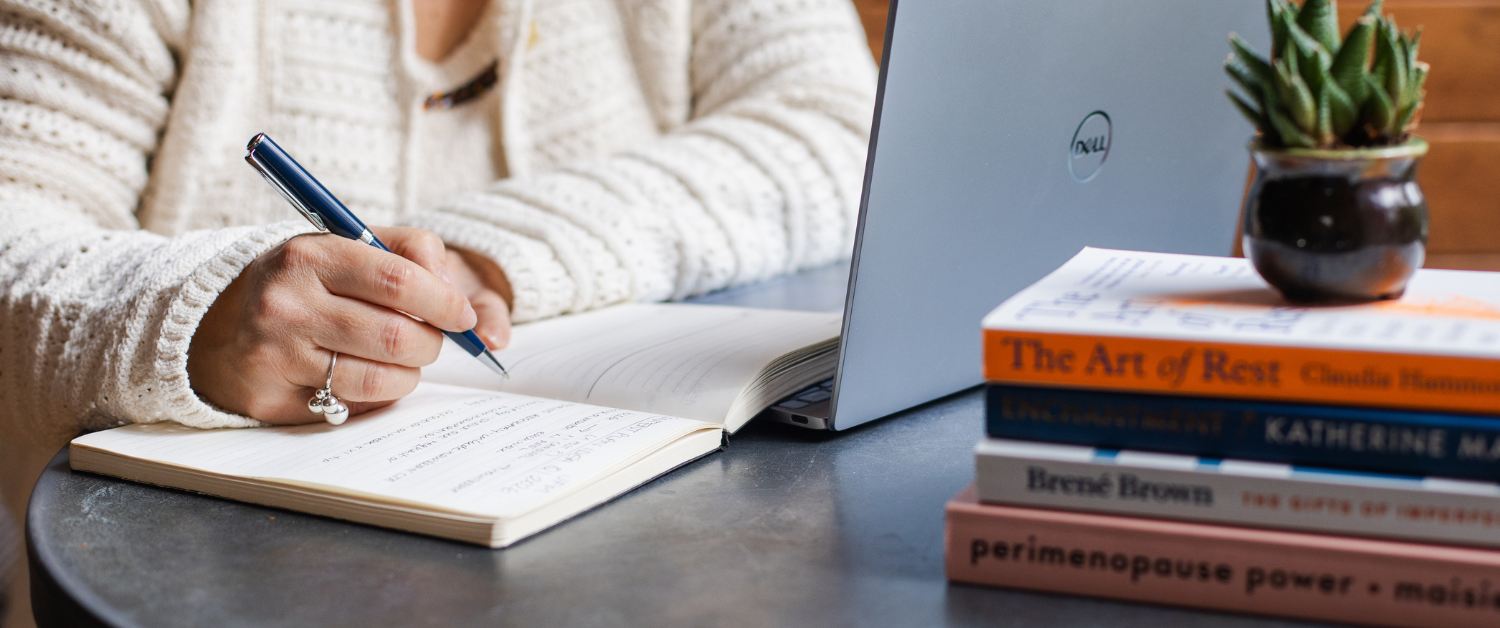 Notebook, laptop and books on menopause and wellbeing while Sarah Robinson tracks symptoms and reflects on changing from Evorel Sequi to Evorel Conti HRT.